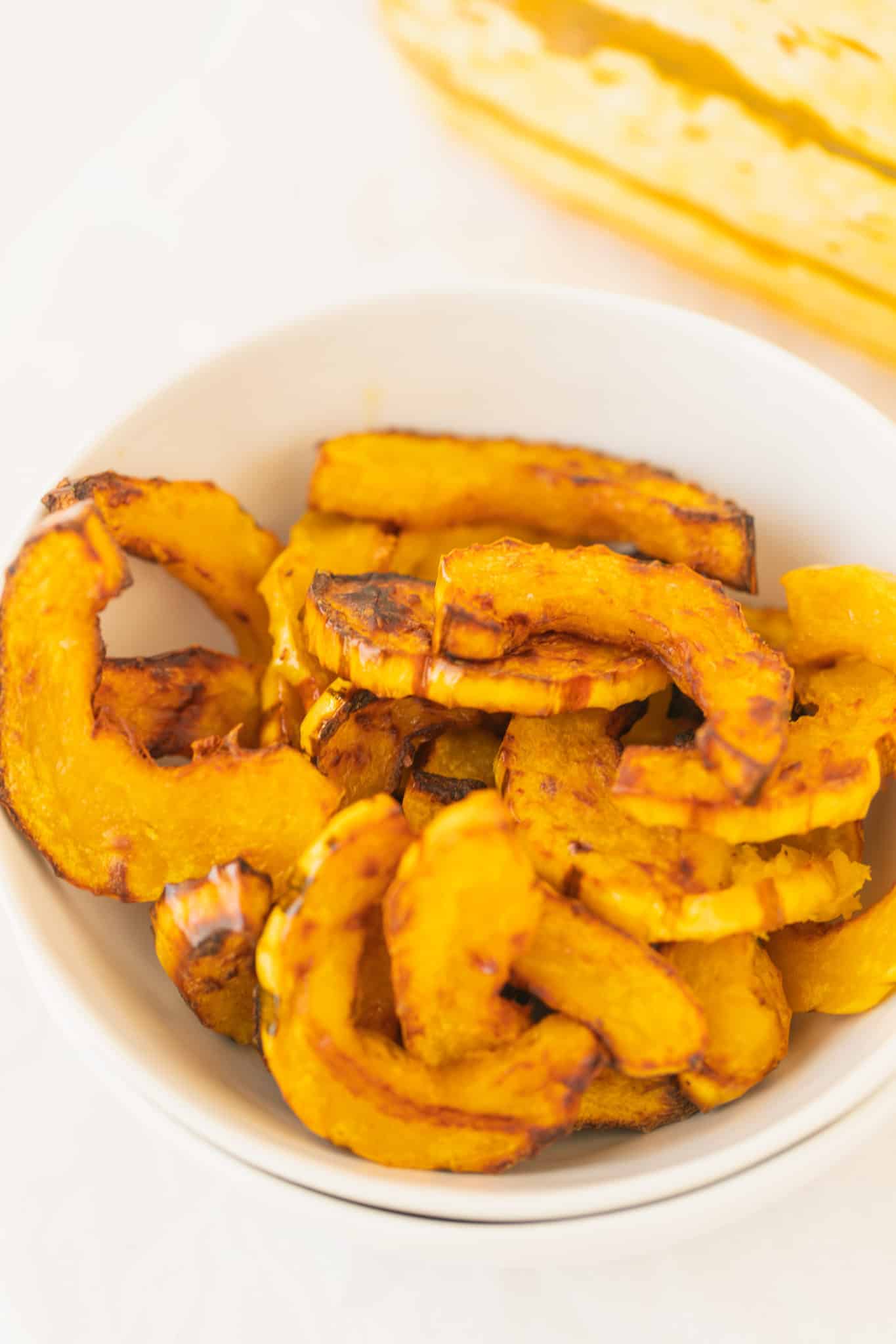 bowl of roasted delicata squash ready to be eaten.
