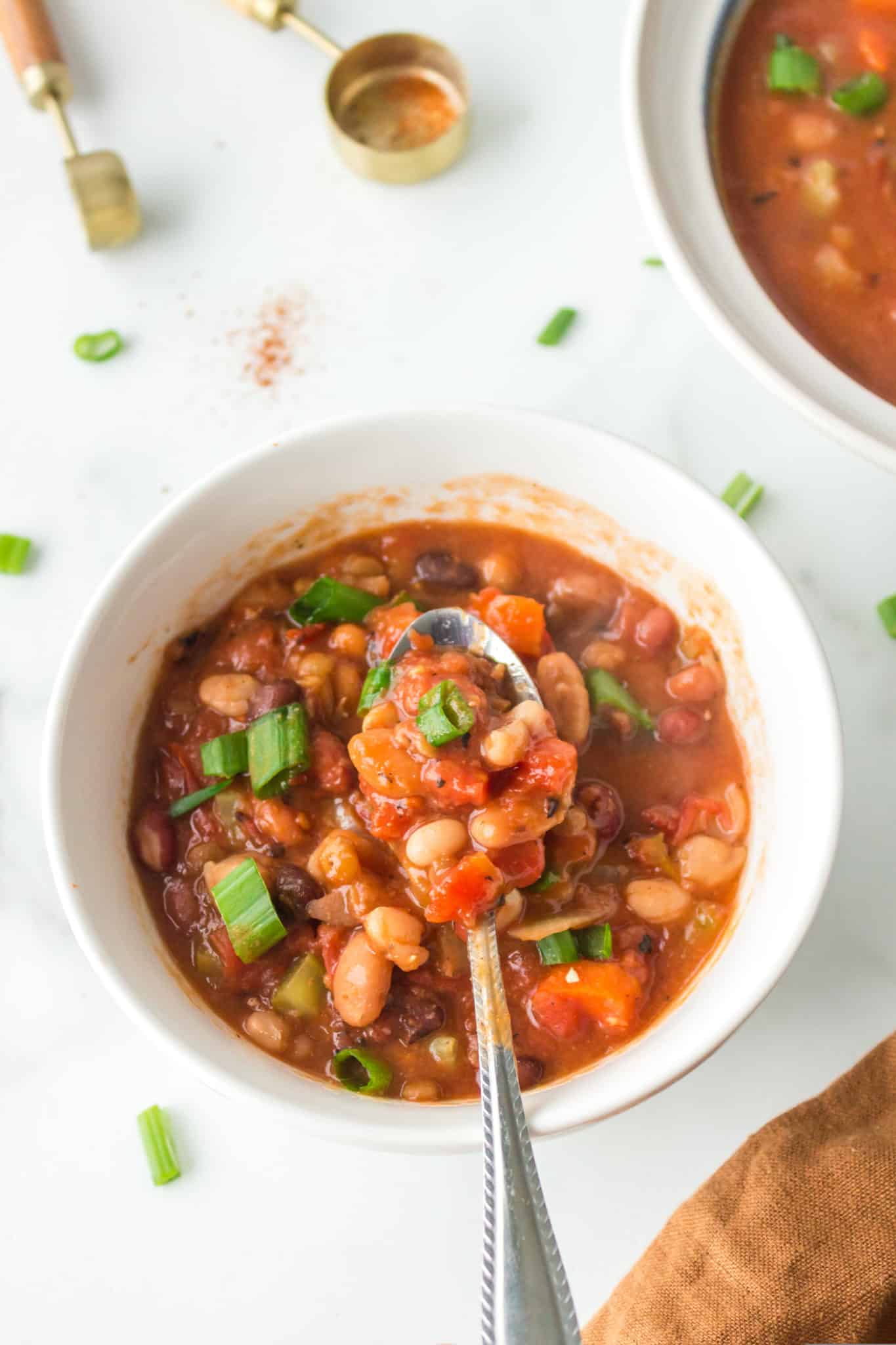 bowl of cooked bean soup with a spoon in it.