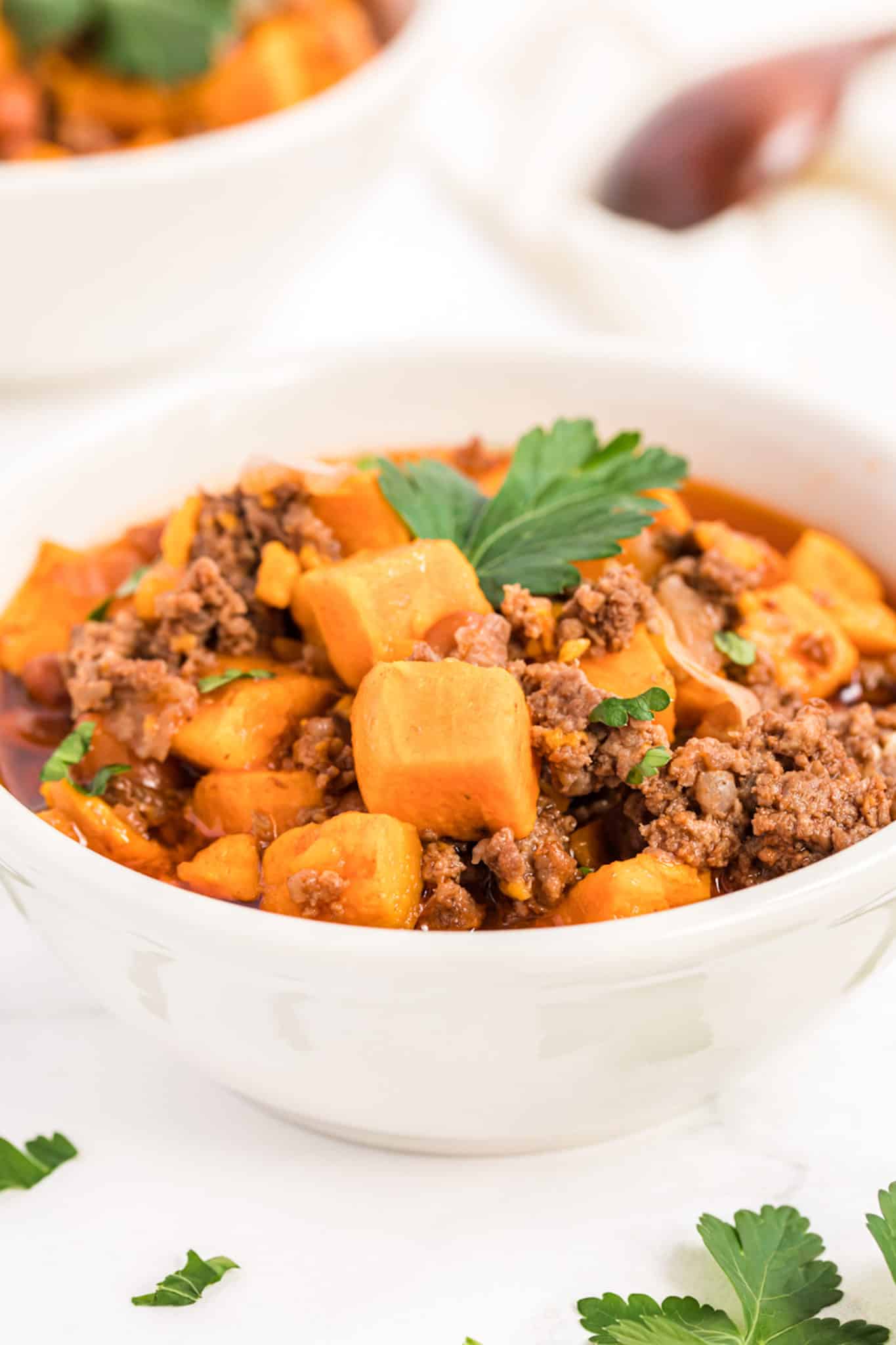 bowl filled with sweet potato chili and topped with fresh parsley.