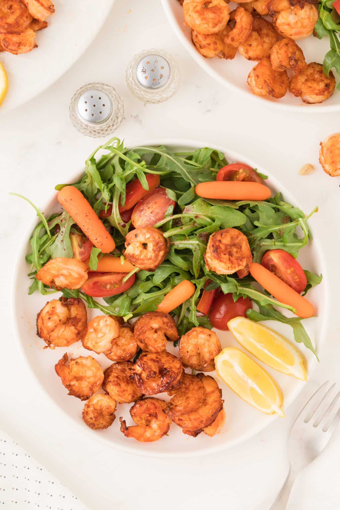Lemon garlic air fried shrimp with salad on a plate.