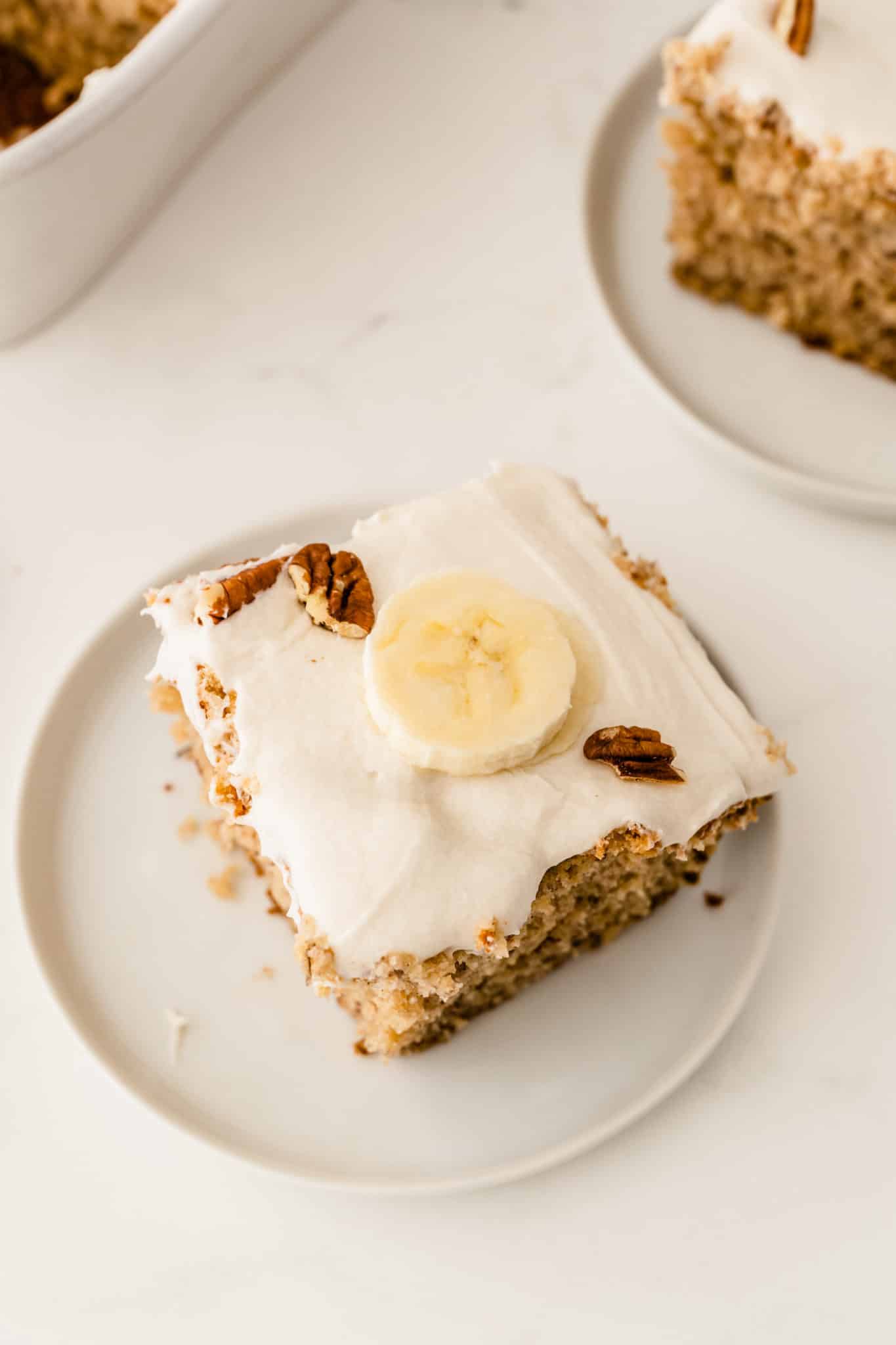 square slice of banana cake with a piece of banana on top.