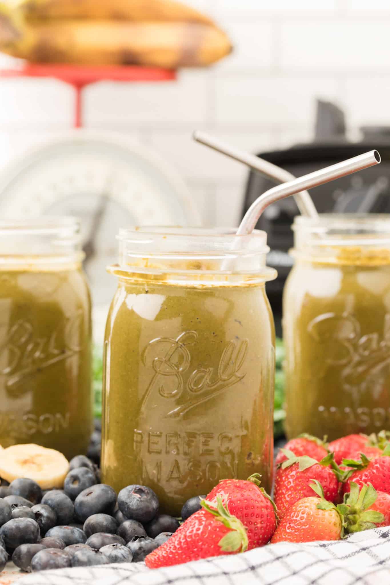 collard green smoothie served in jar with metal straws