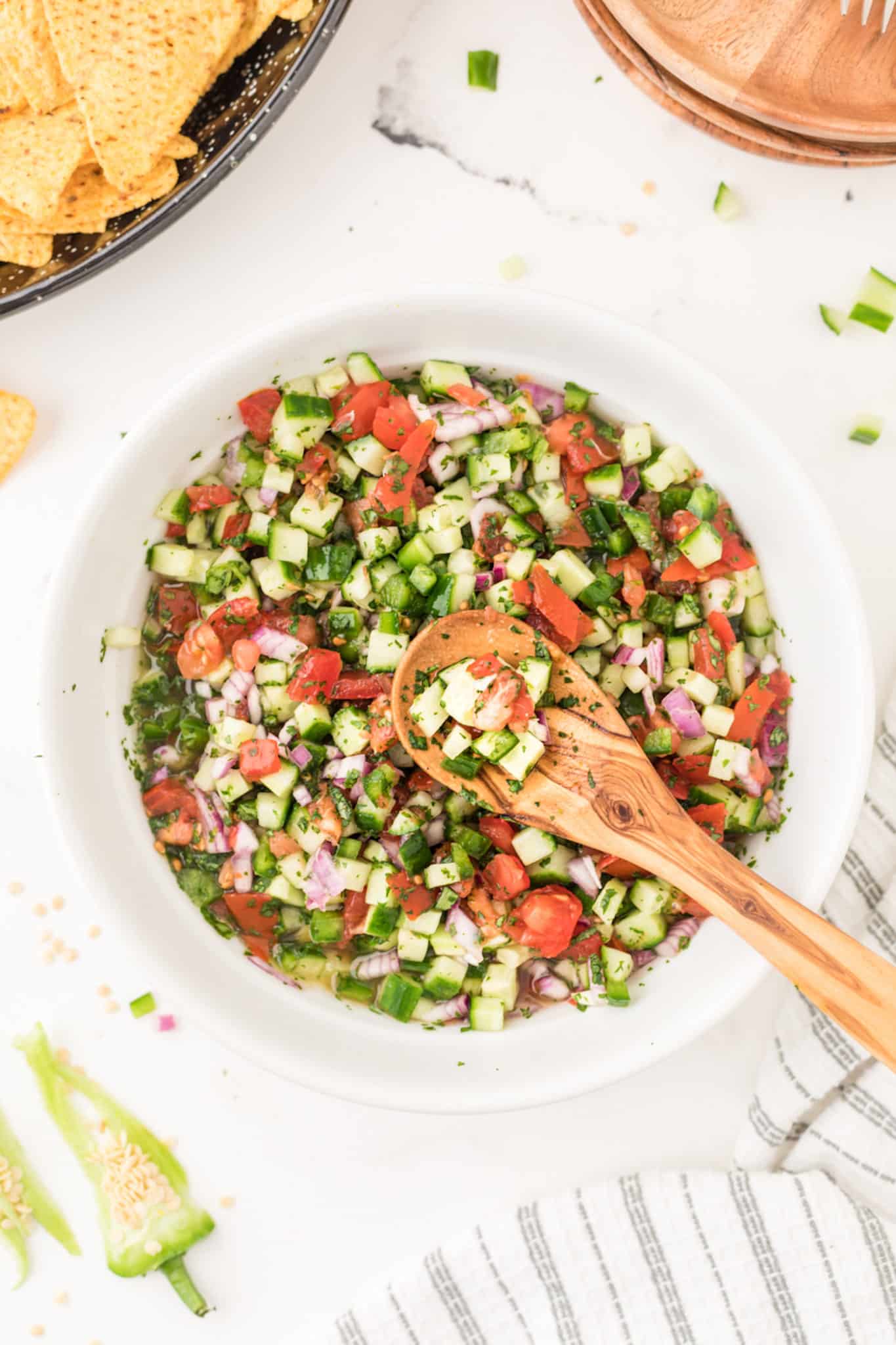 bowl of salsa with a wooden spoon on table