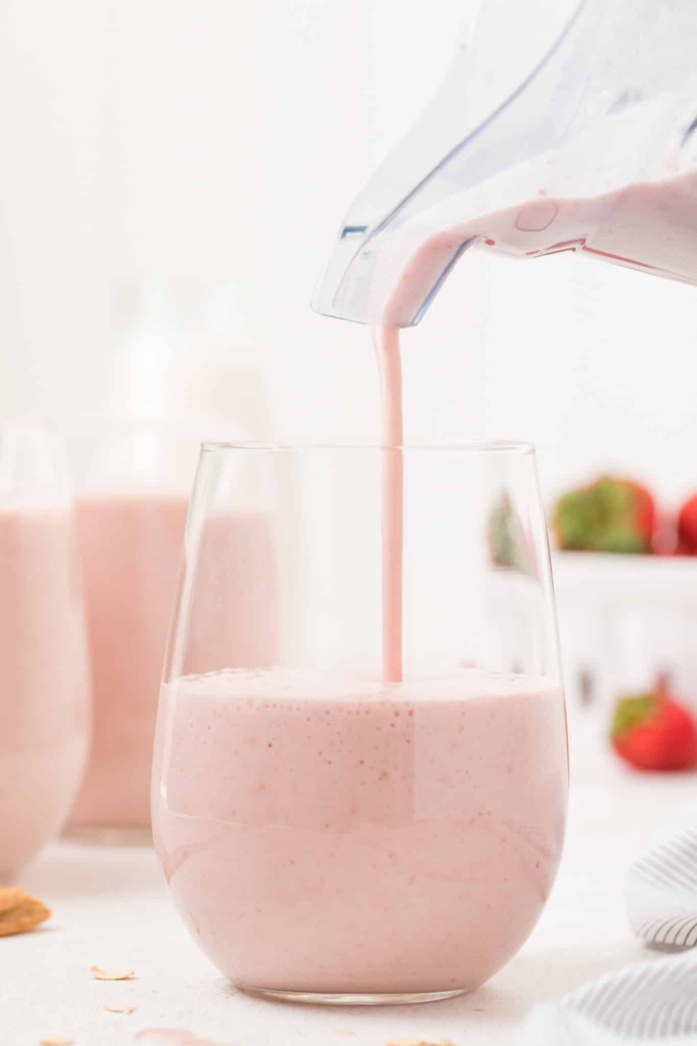 Pouring a strawberry smoothie into a glass.