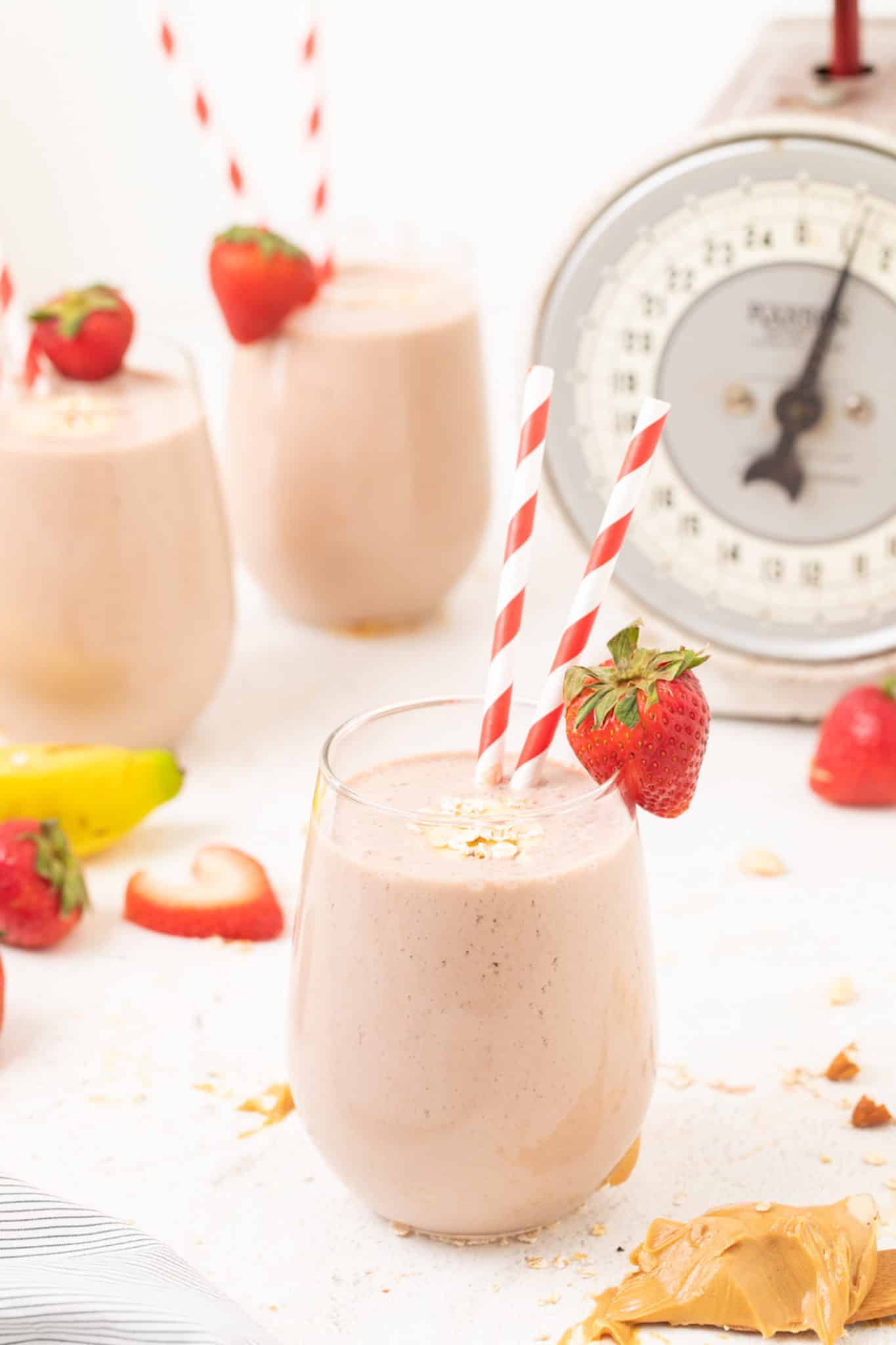 three glasses of strawberry smoothie served with straws.