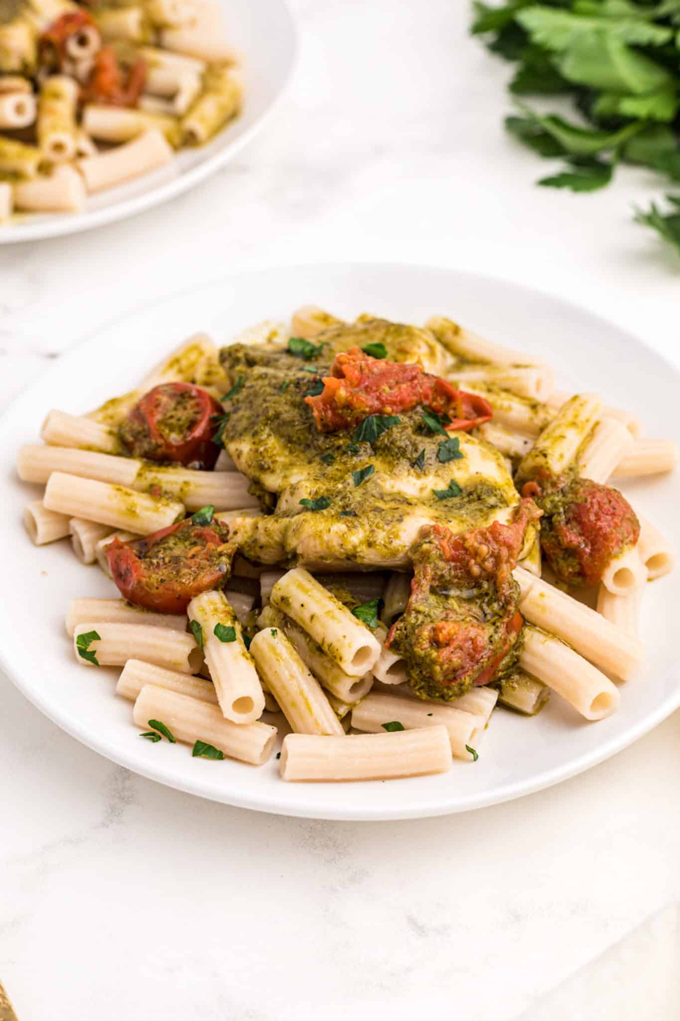 instant pot pesto chicken served with pasta and tomatoes.