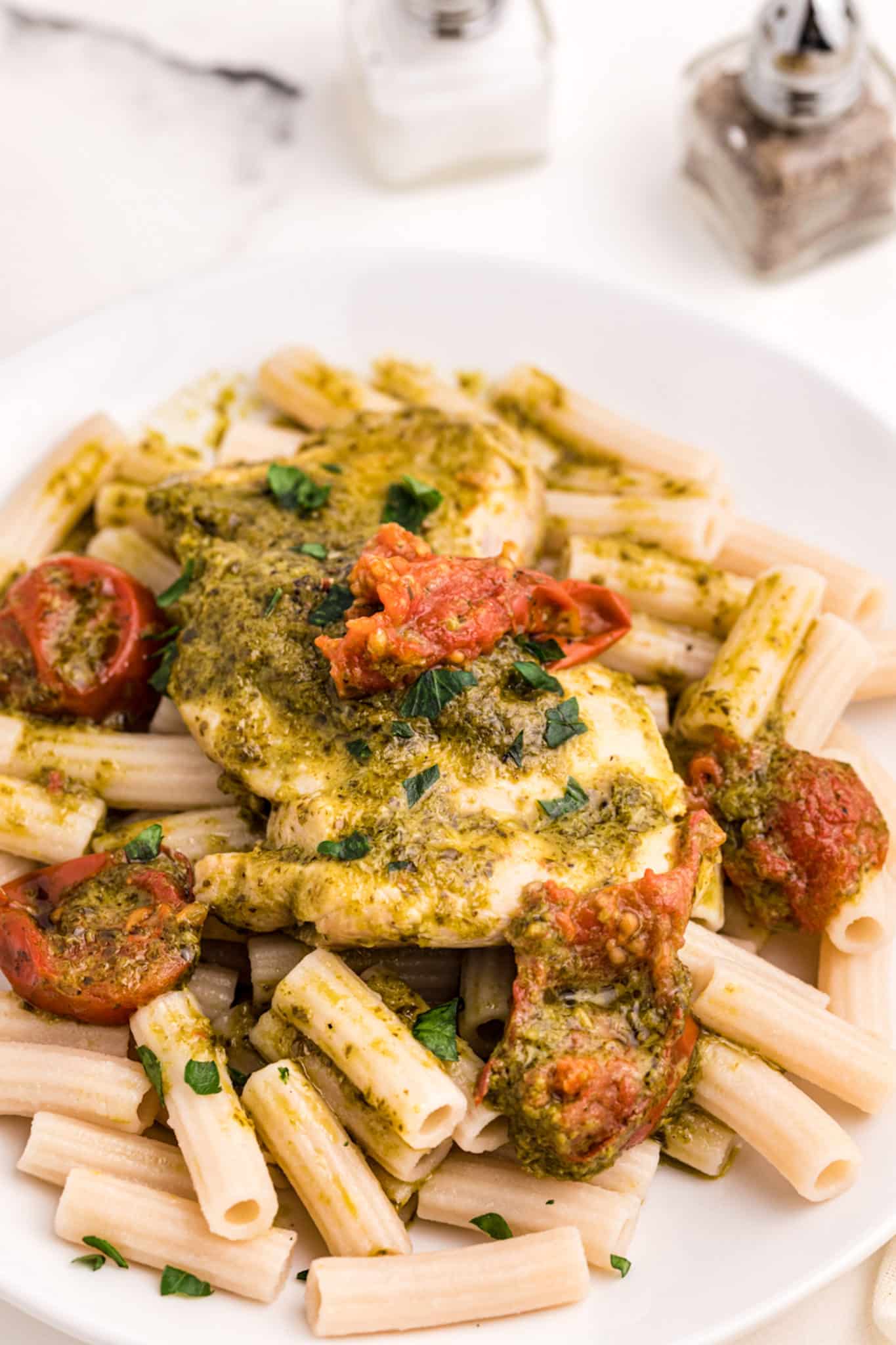 pesto chicken with pasta served on white plate.