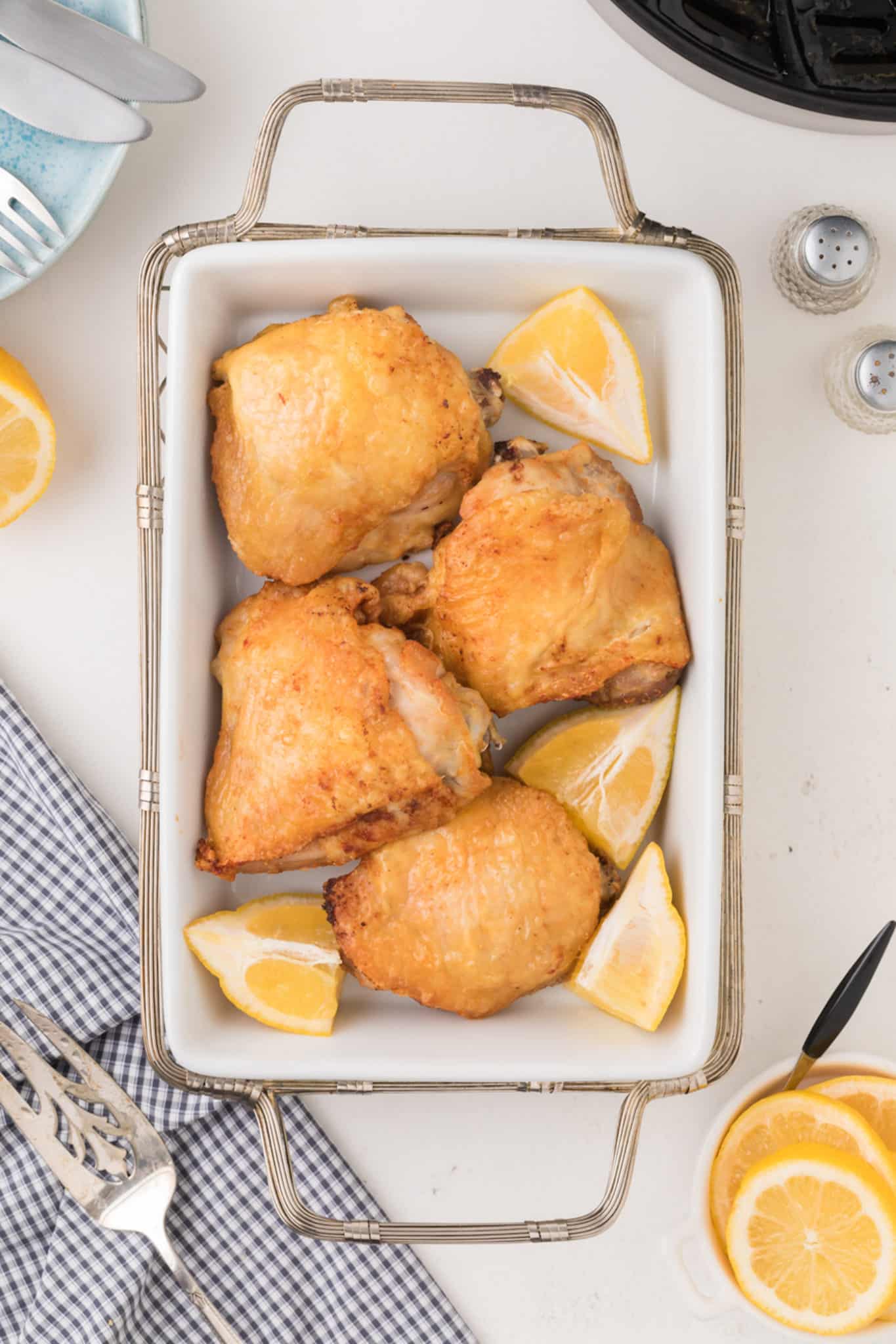 platter of air fried chicken thighs bone in with lemon wedges.