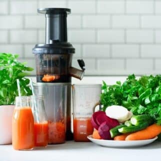 vegetable juicer on table with fresh vegetables.