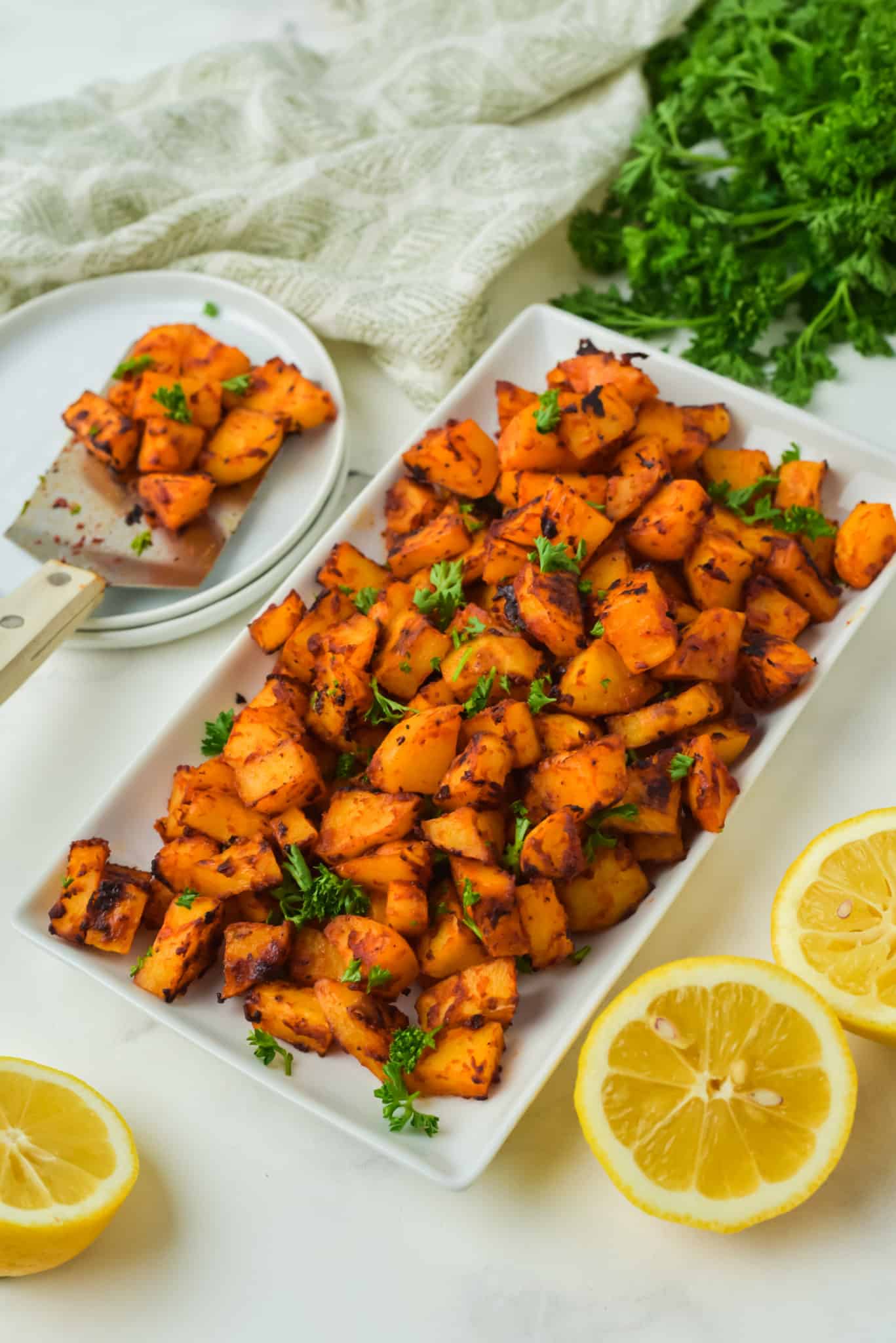 Angled view of a white rectangle plate filled with diced Spanish potatoes.