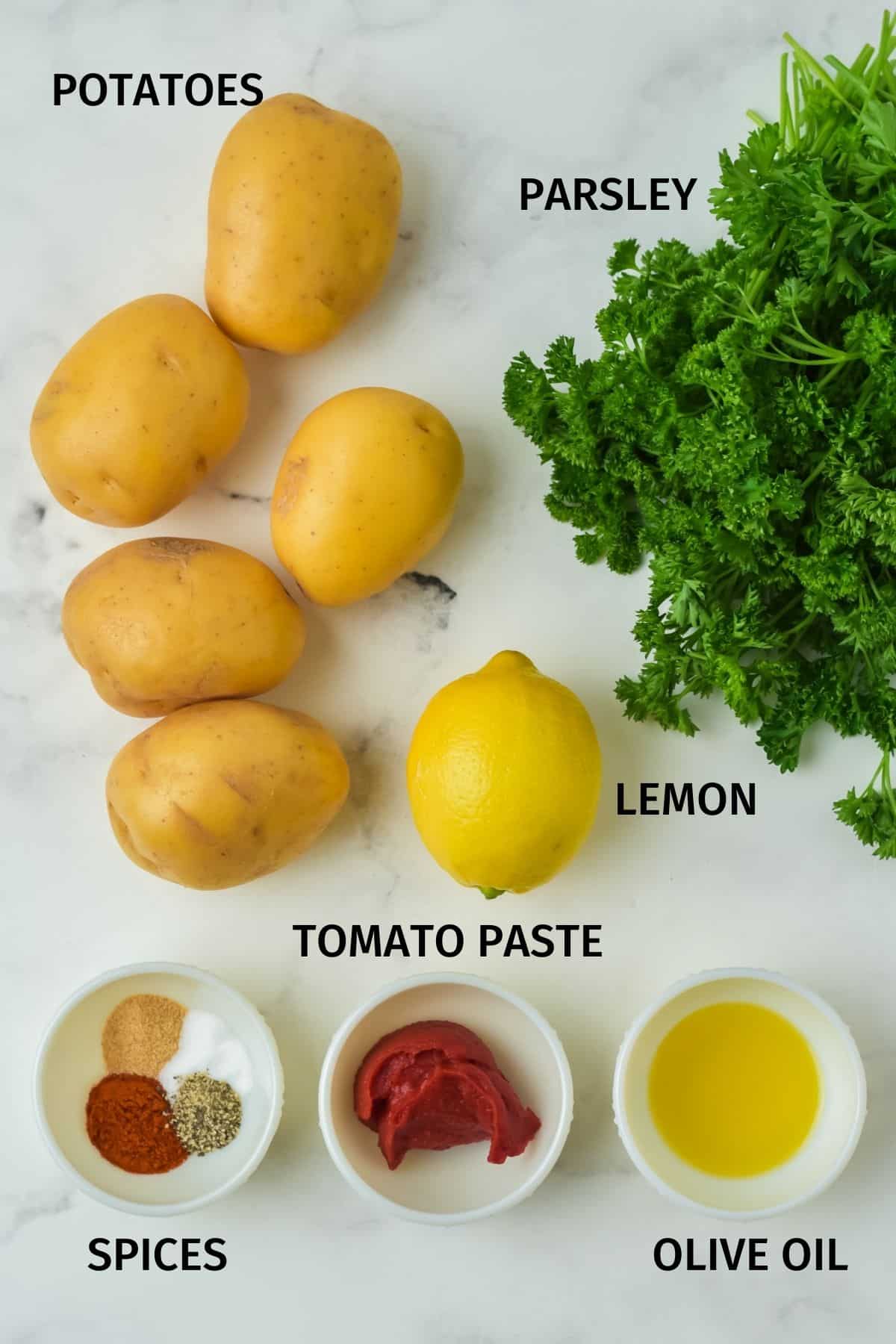 Ingredients for Spanish potatoes on a white marble surface.