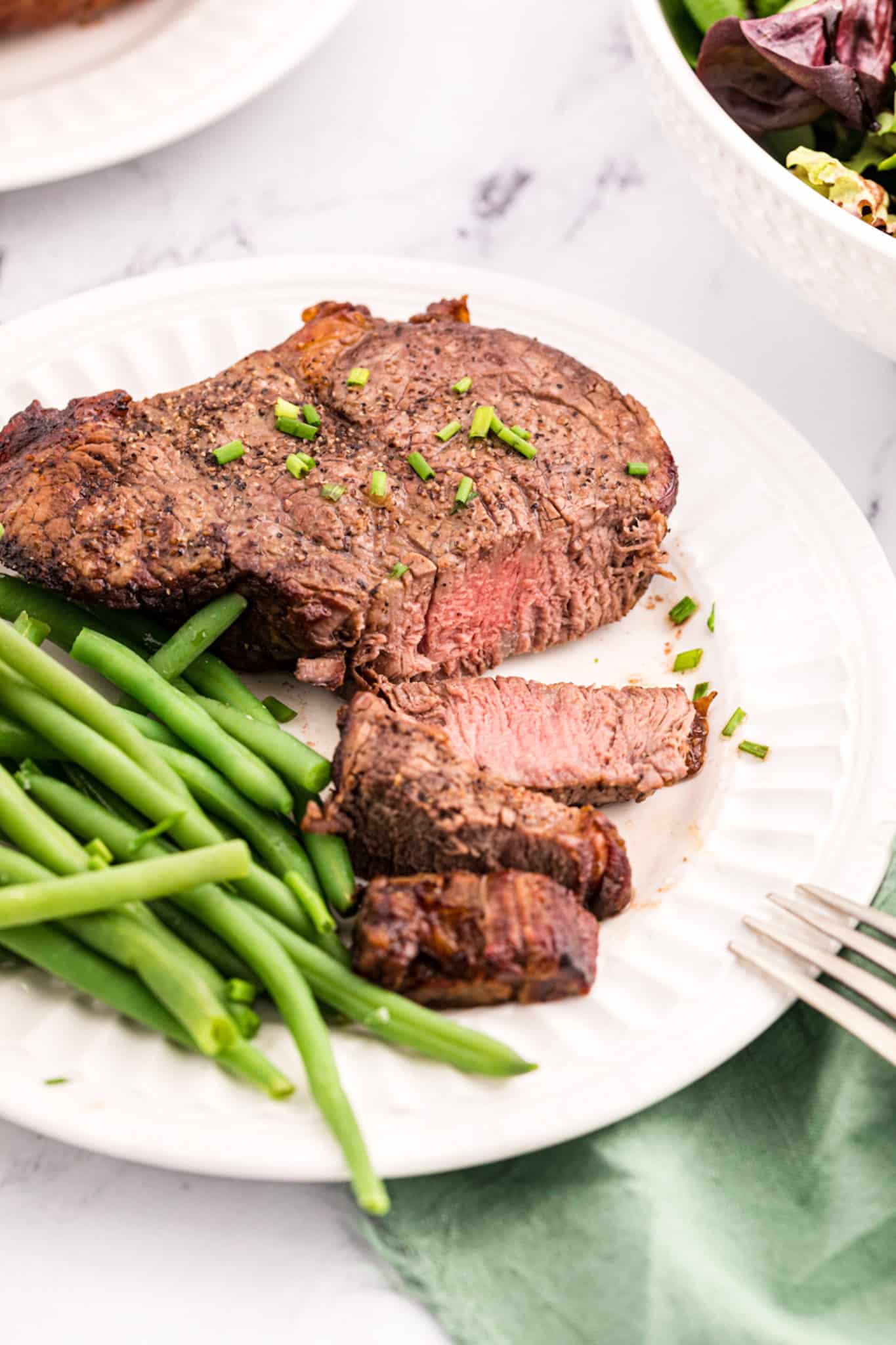air fried filet mignon served on plate with green beans.