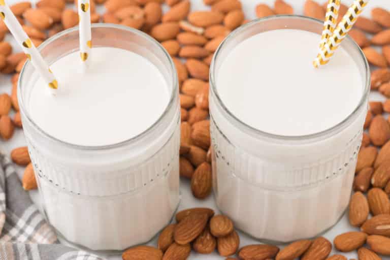 Two glasses of almond milk, each with two paper straws.