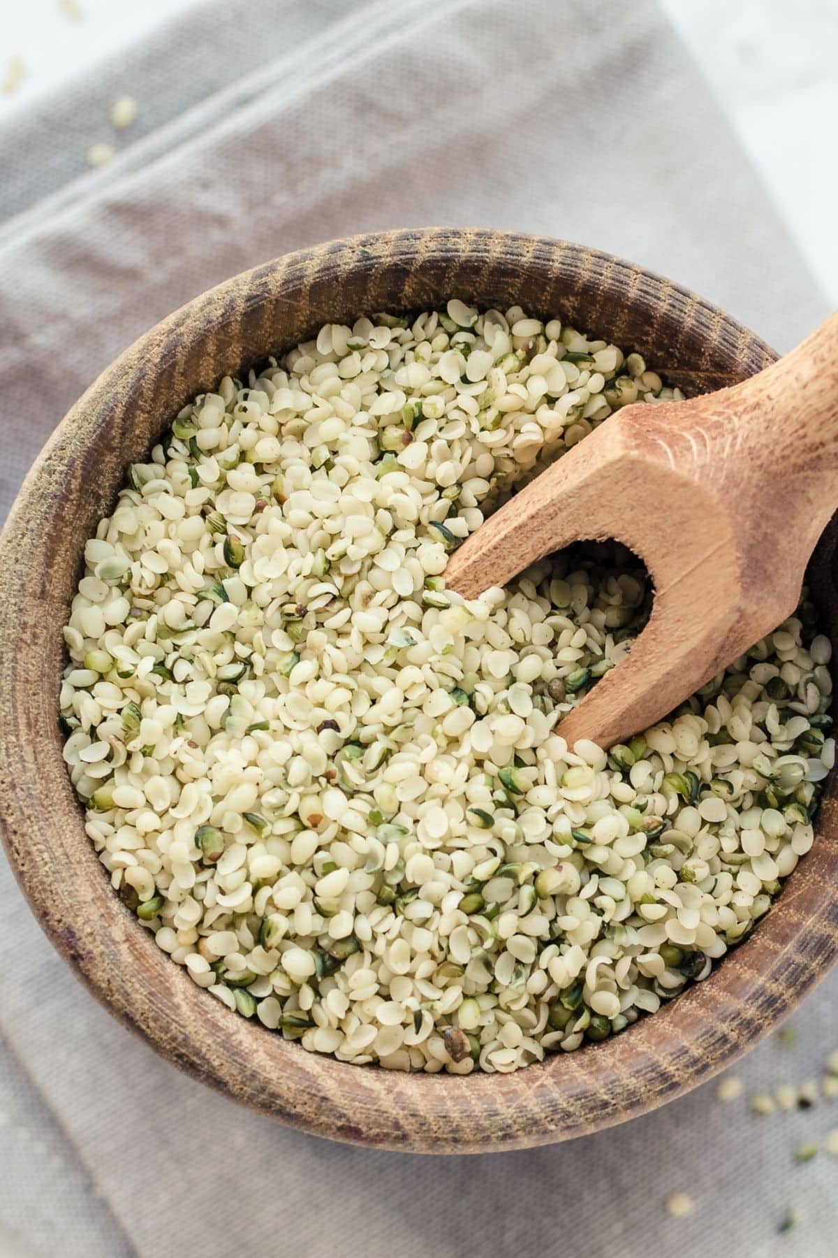 hulled hemp seeds in a wooden bowl with a spoon.