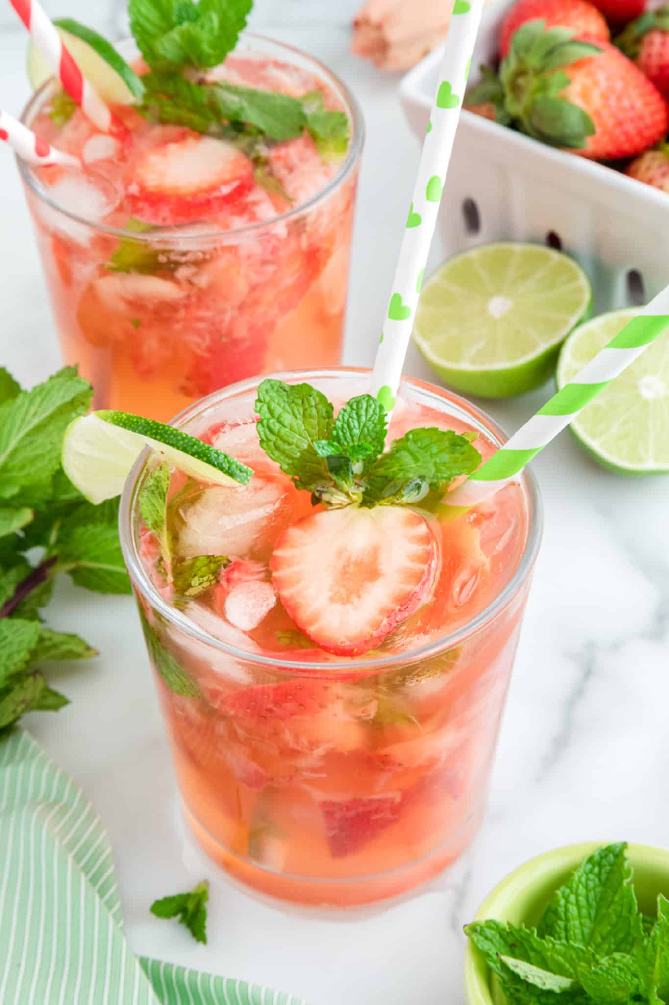 strawberry mocktail served in glass with striped green and white straws.