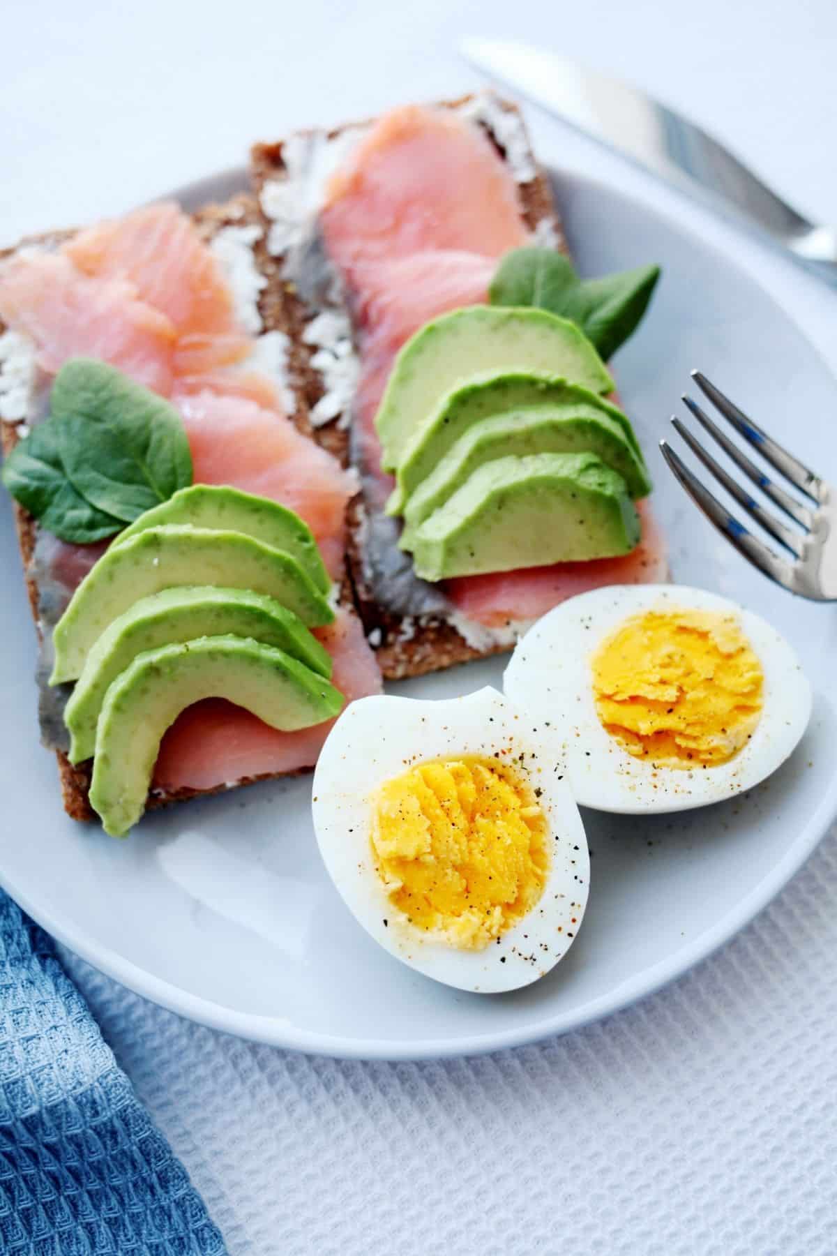 Plate of eggs, avocado, fish and flat bread.