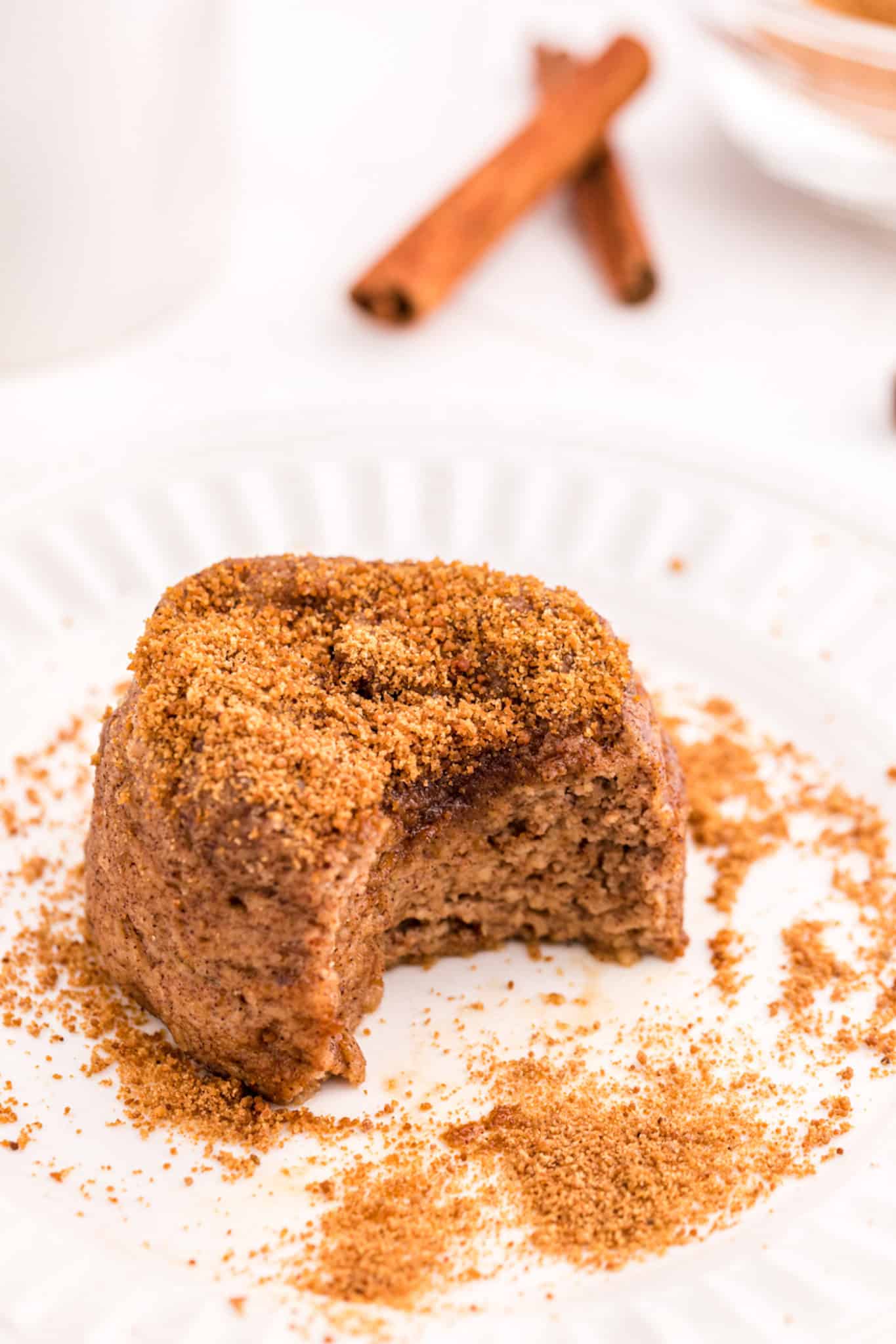 A small snickerdoodle cake with a bite taken from it on a small white plate.