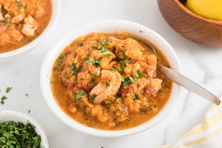 Instant Pot Sweet Potato Chicken stew in a small white bowl with a spoon.