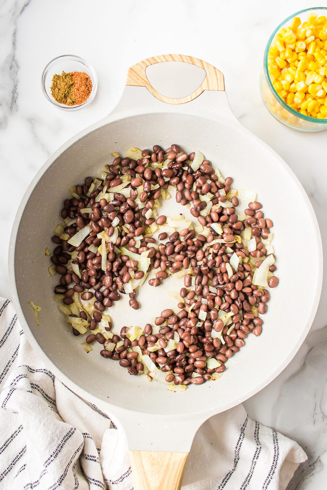 Black beans and onions sauteed in a skillet.