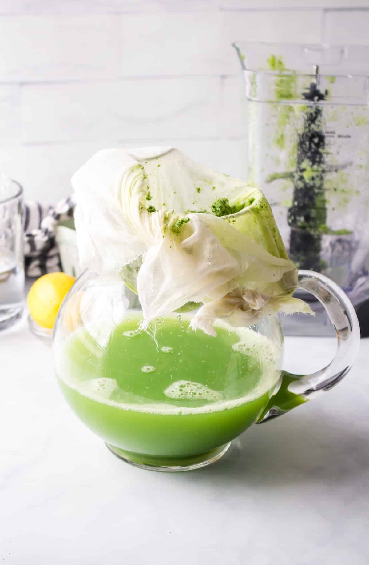 straining green juice into pitcher.