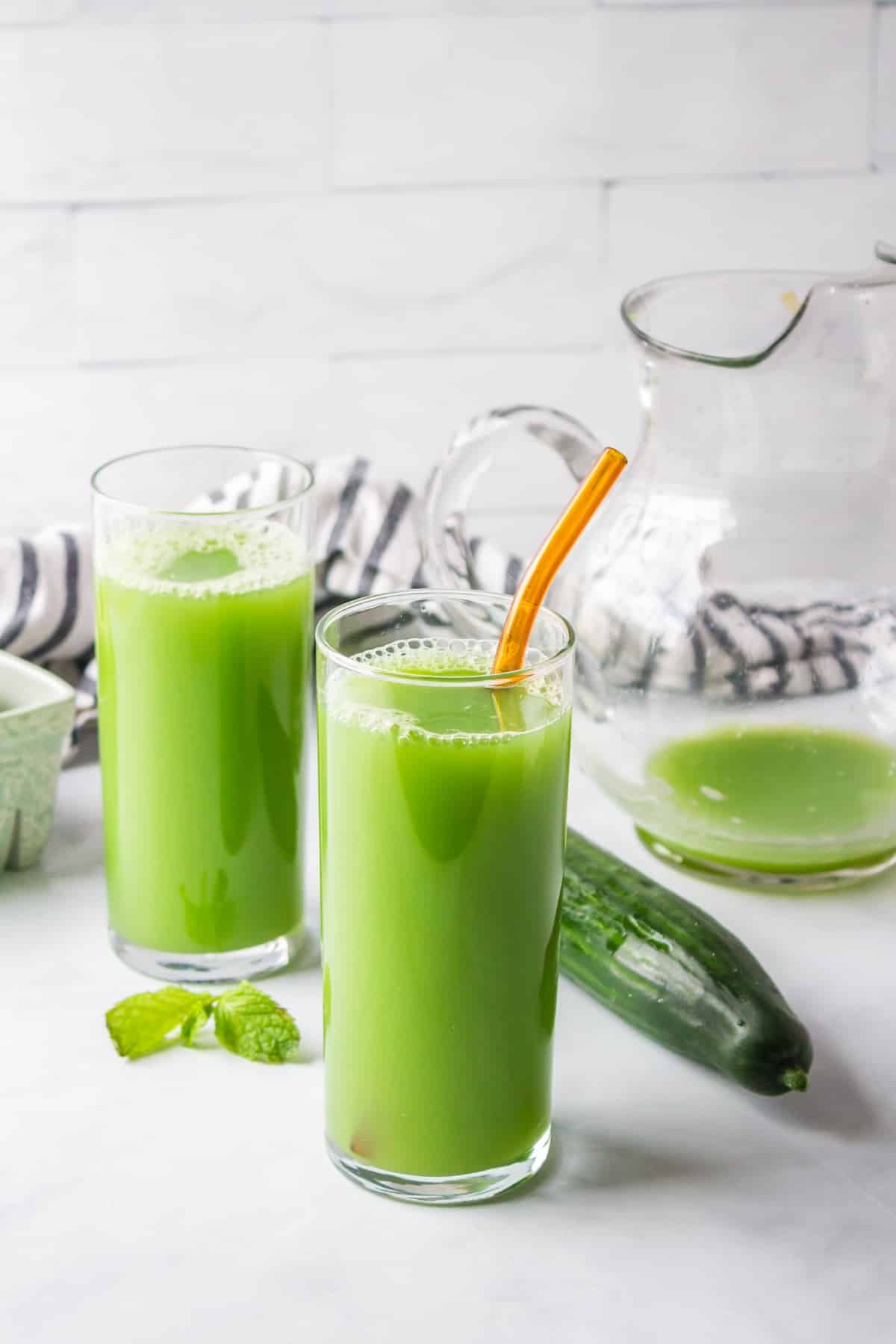 two glasses of cucumber green juice ready to drink.