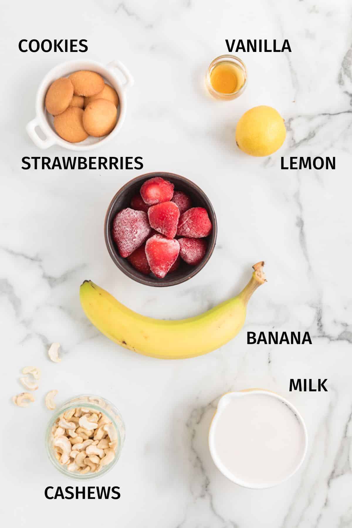 Ingredients to make Strawberry Cheesecake Smoothie on a white surface.