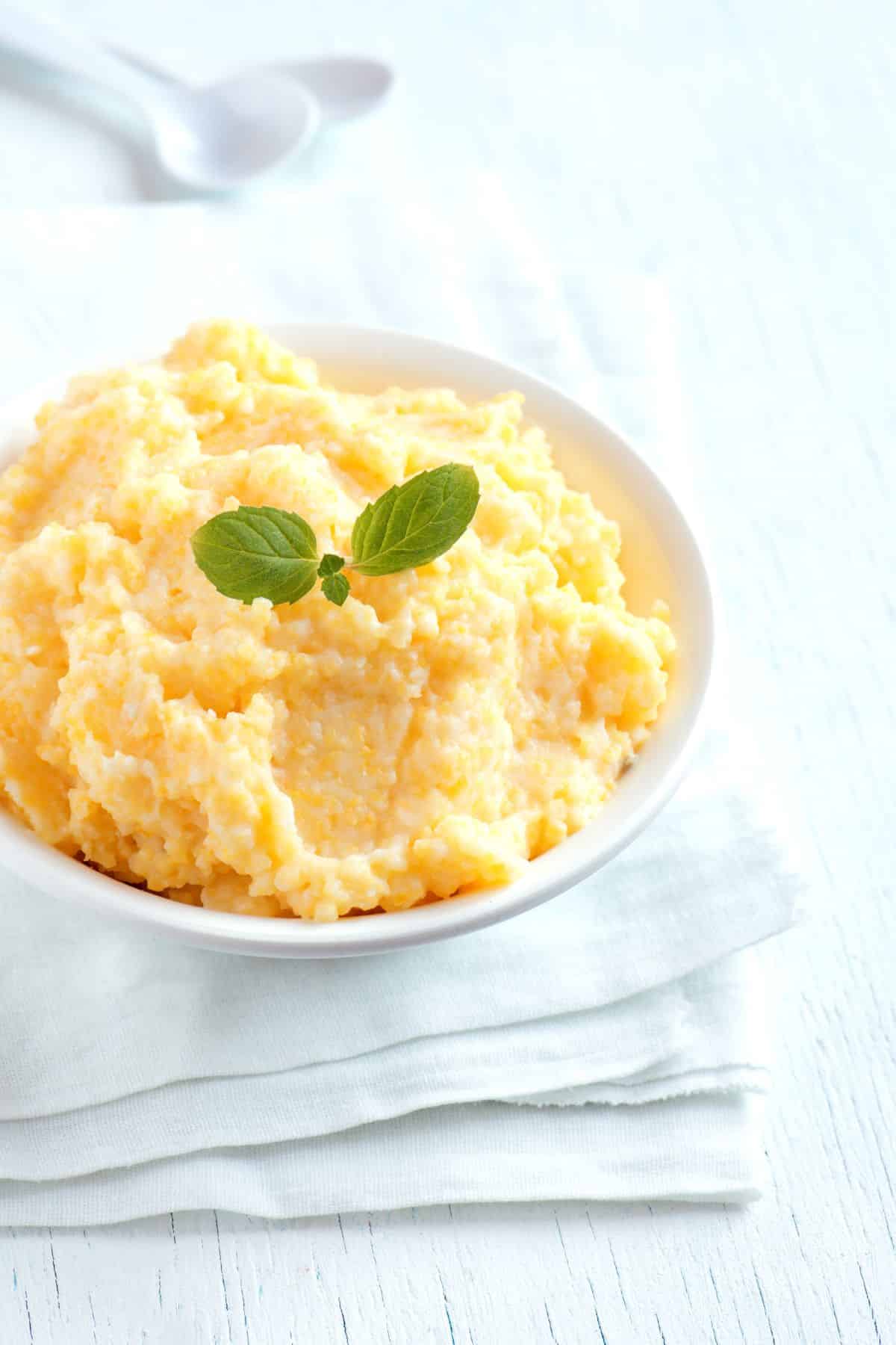 Bowl of polenta on white cloth and wooden surface.