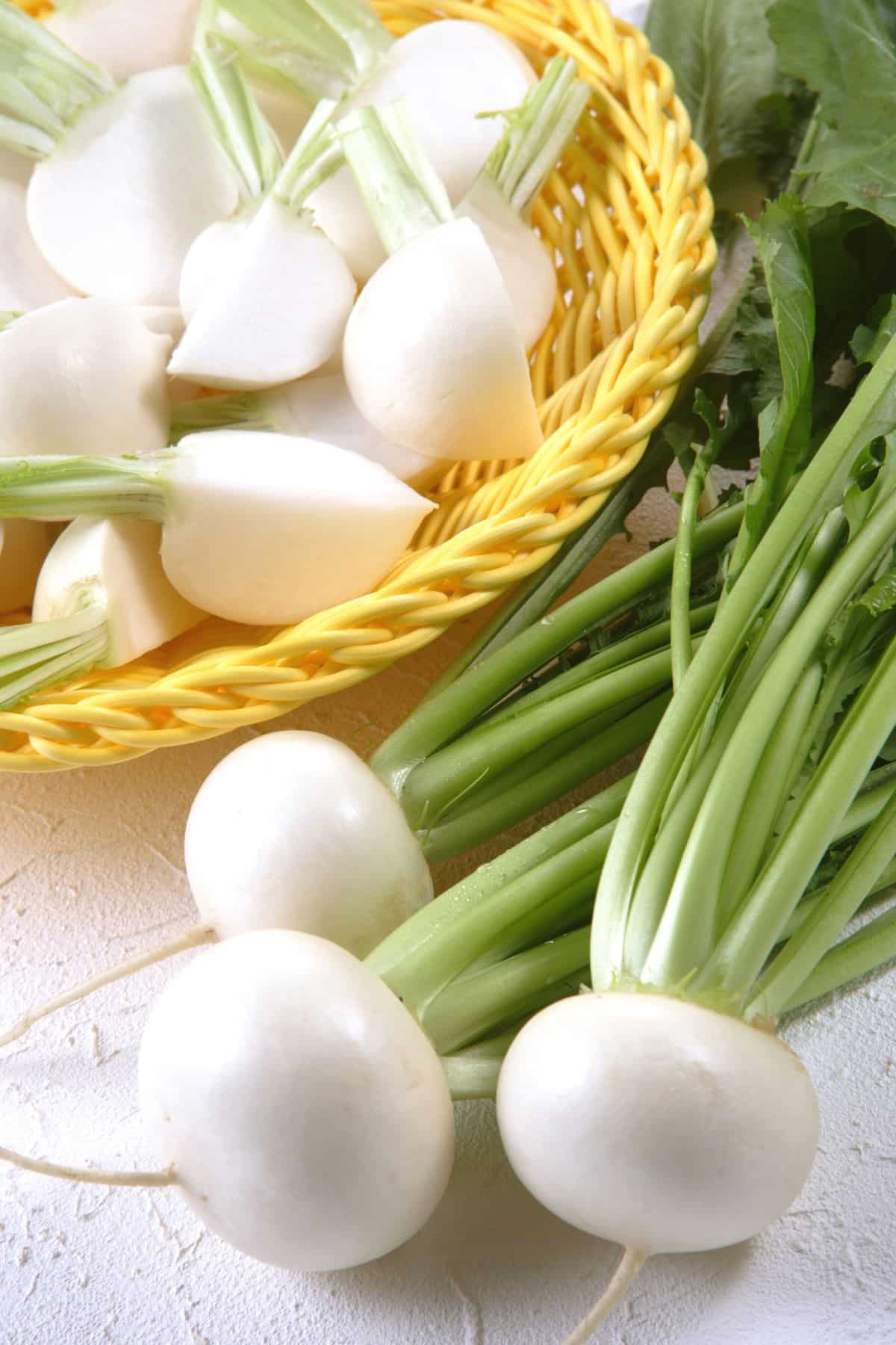 Whole turnips beside basket of cut up turnips.