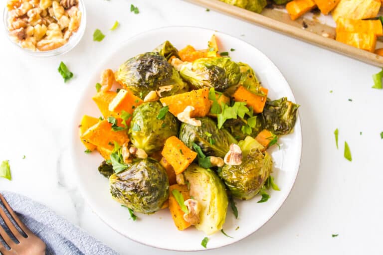 Roasted brussels sprouts and sweet potatoes on a white plate.