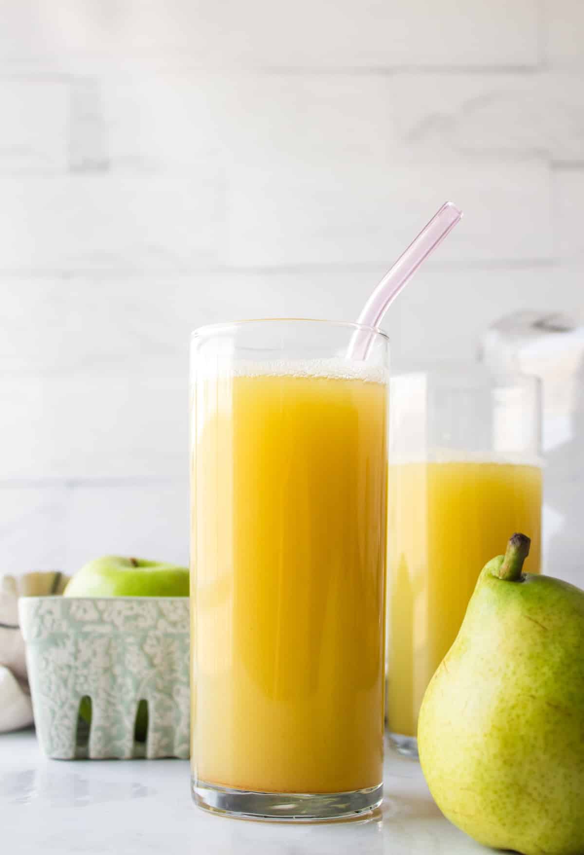pretty yellow pear juice in clear glass with straw.