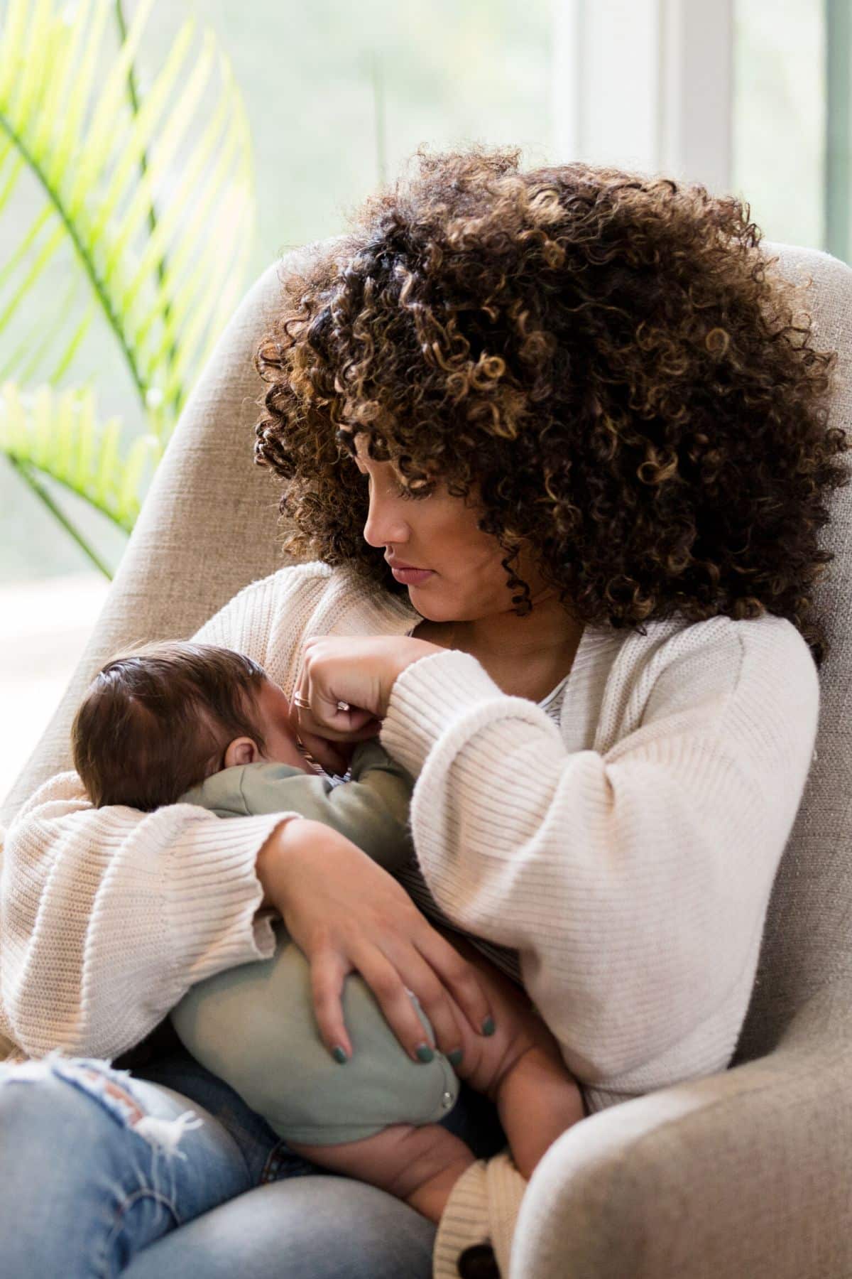 Woman in an armchair breastfeeding her infant.