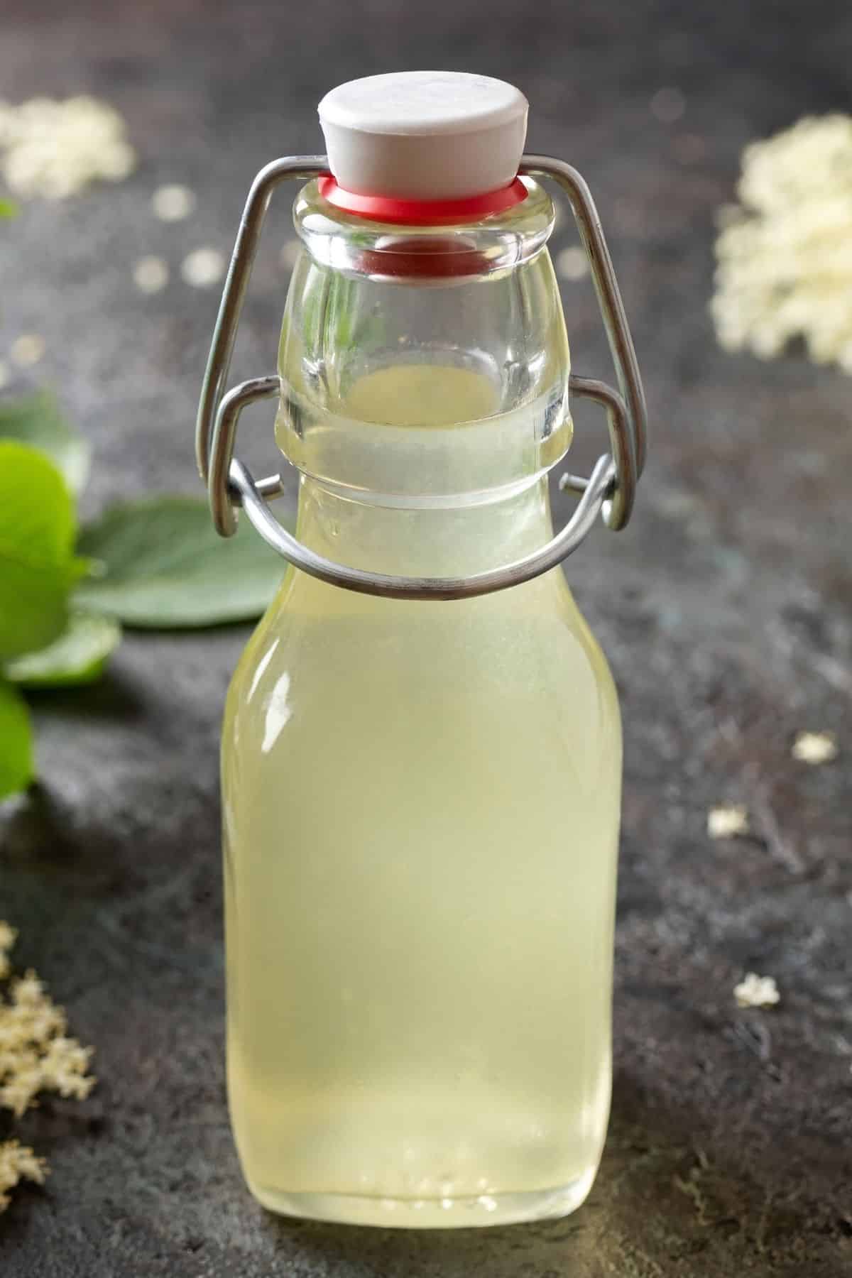 Jar of simple syrup on dark surface.
