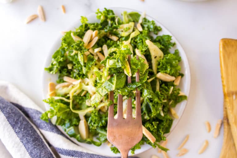 A forkful of kale salad over a serving bowl.