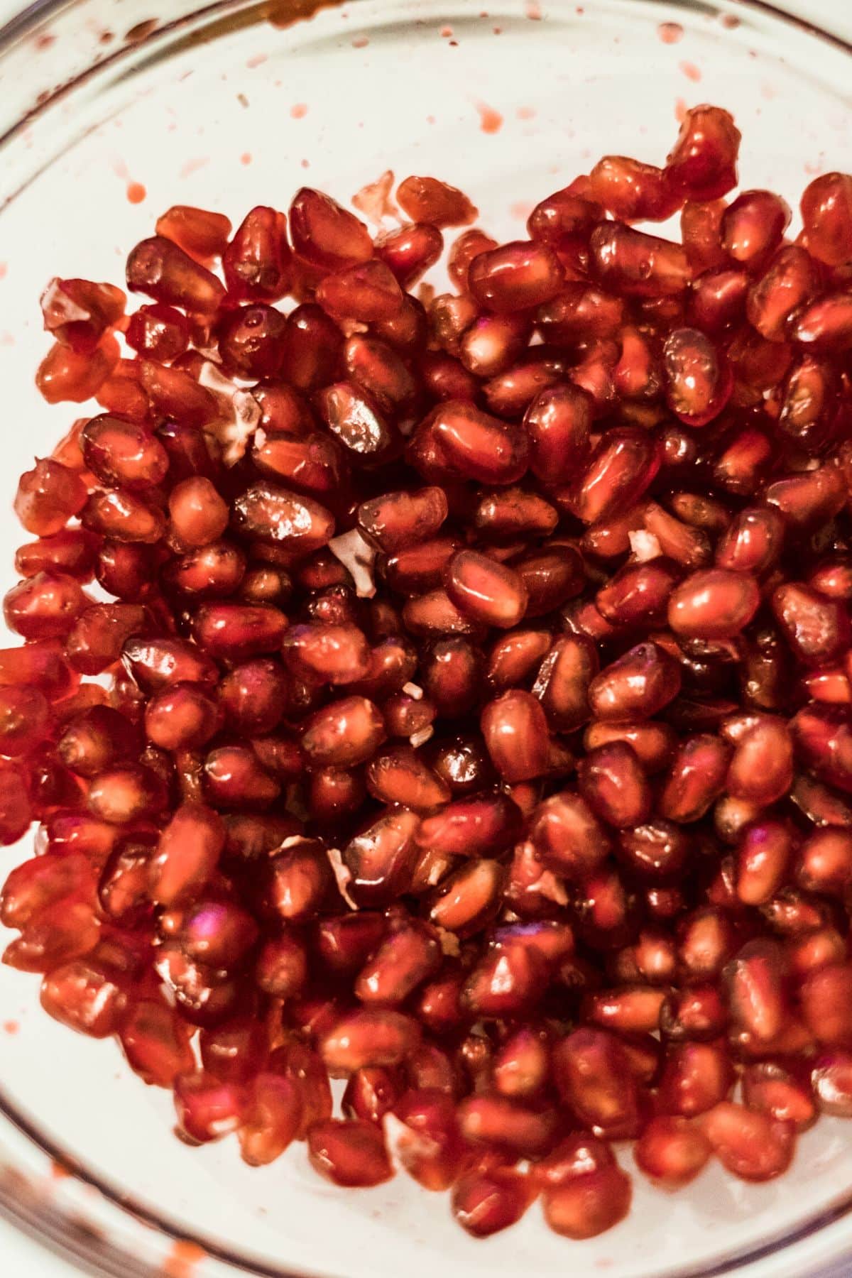 A glass mixing bowl filled with pomegranate arils.