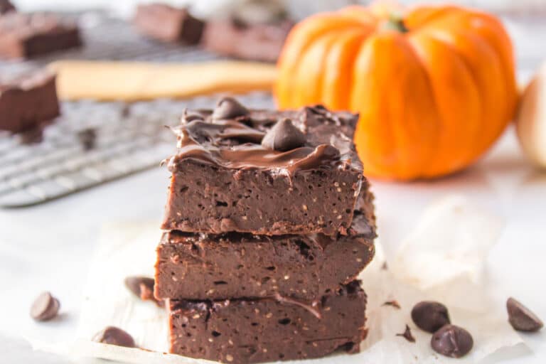 Three vegan pumpkin brownies stacked on a white counter.