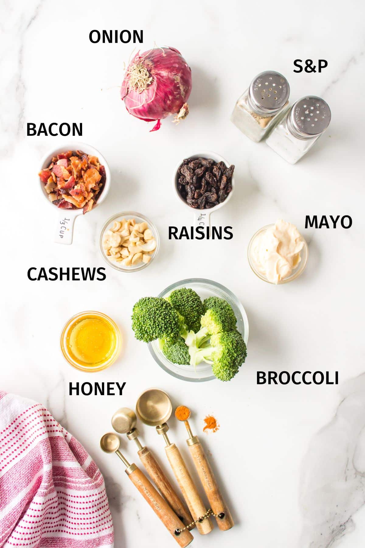 Ingredients to make Broccoli Salad in small bowls on a white surface.