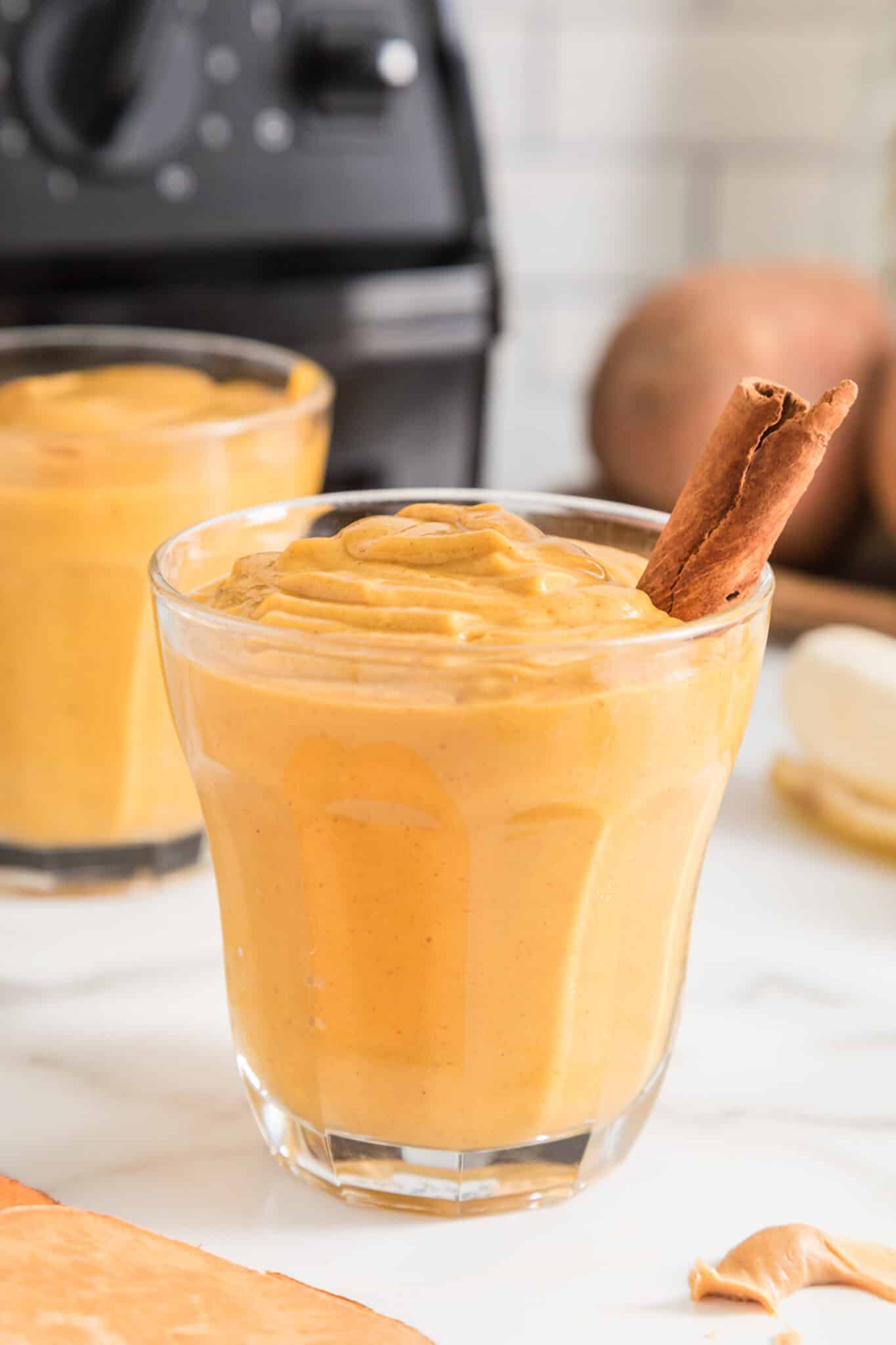 Small glass filled with vegan sweet potato smoothie and a cinnamon stick.