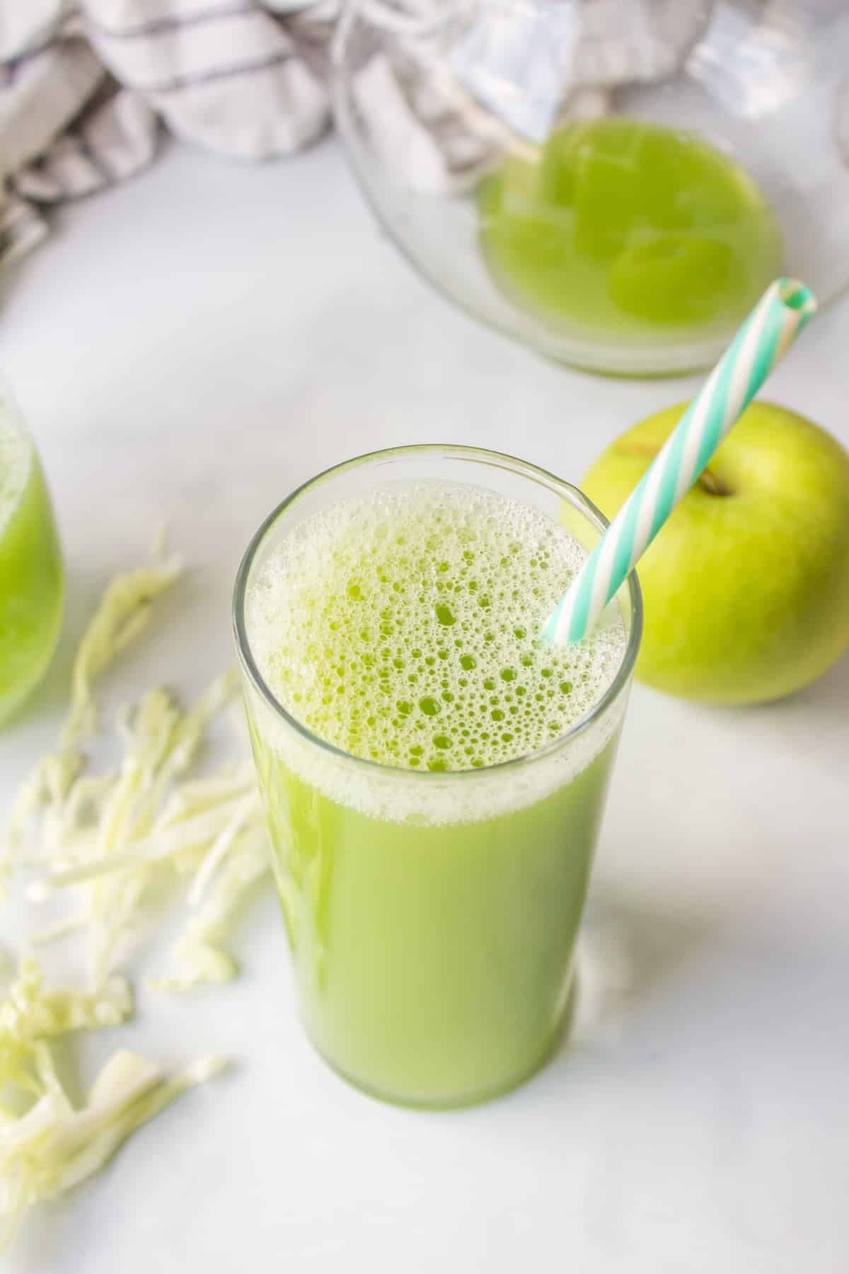 pretty glass filled with green juice and a striped straw.