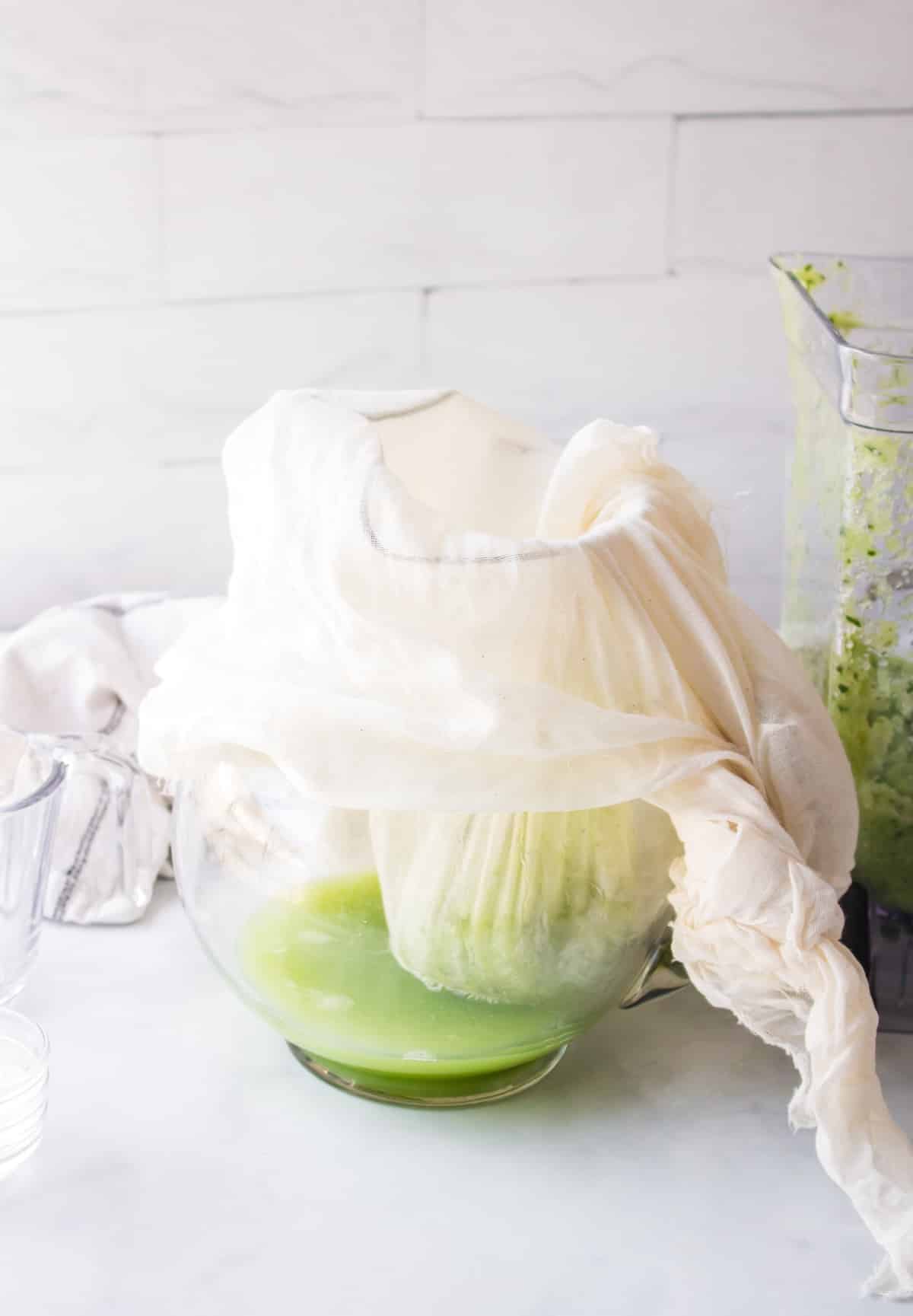 straining cabbage juice with muslin cloth in a pitcher.
