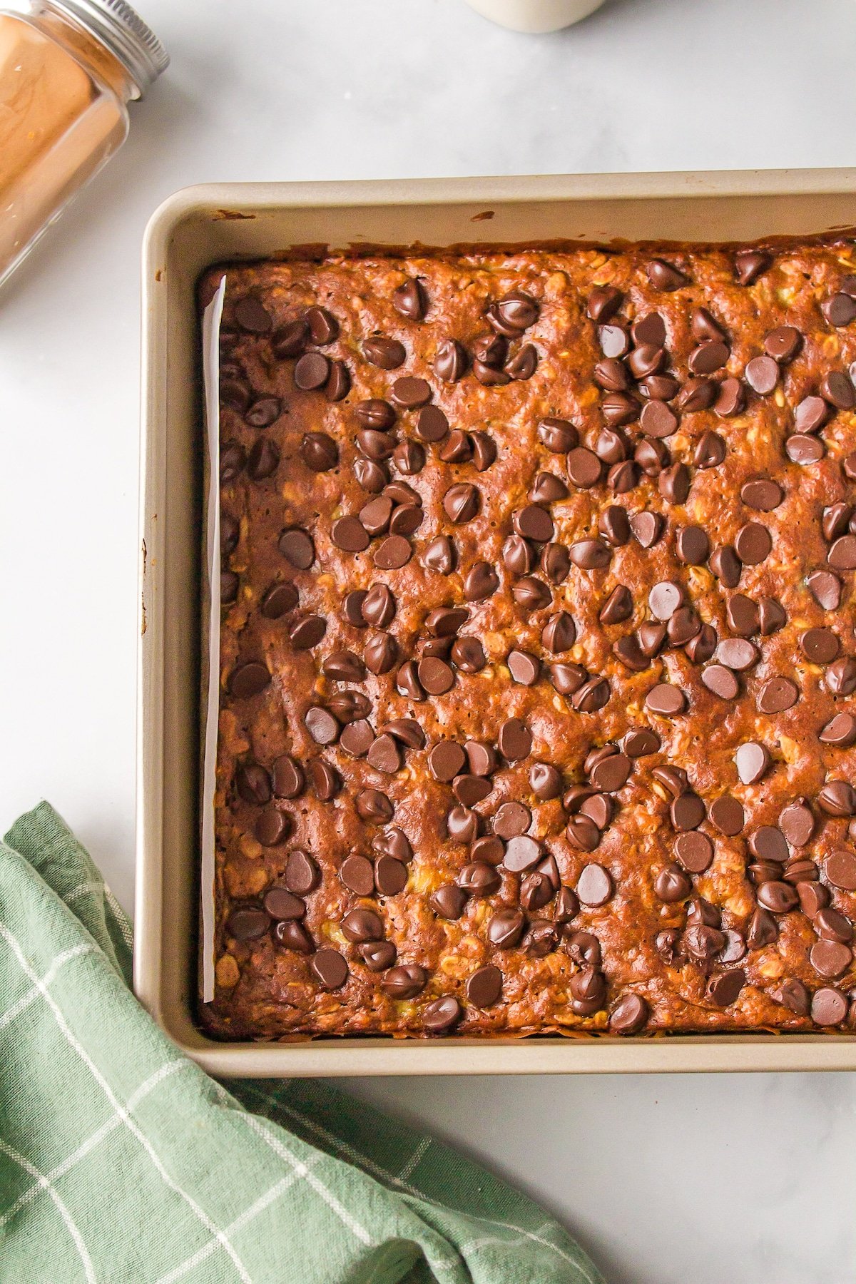 A metal baking dish lined with parchment and filled with banana oat bars.