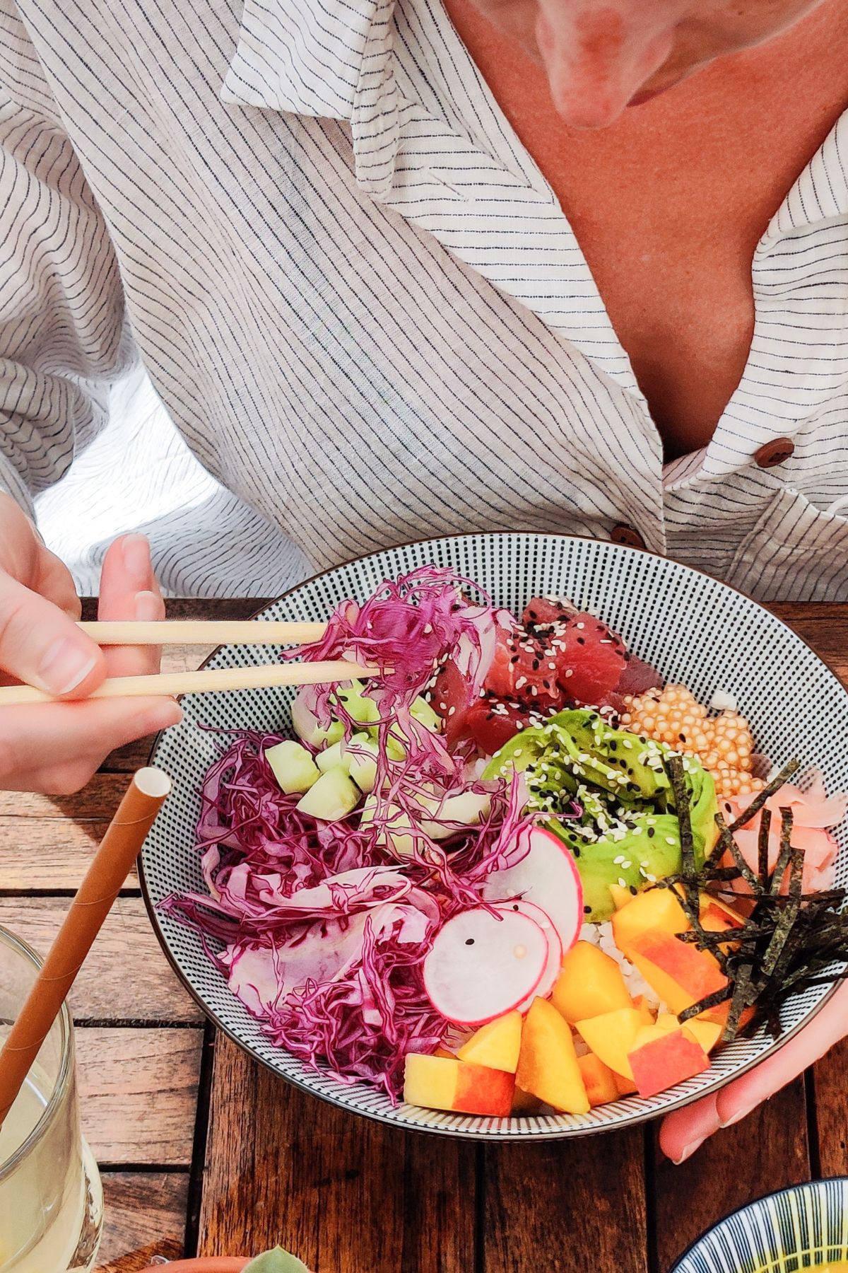 a woman eating a meal with chop sticks.