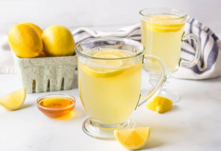 two mugs of honey lemon tea on table.