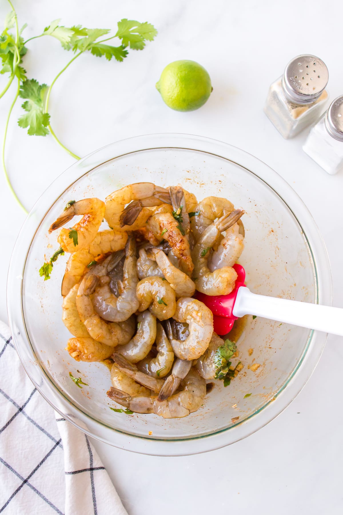 raw shrimp being coated in seasonings and oil.