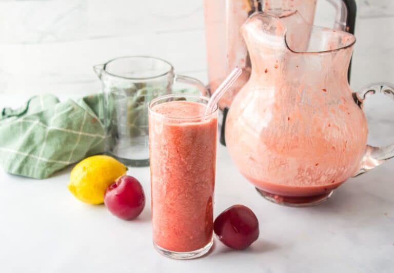 plum juice in glass with pitcher.
