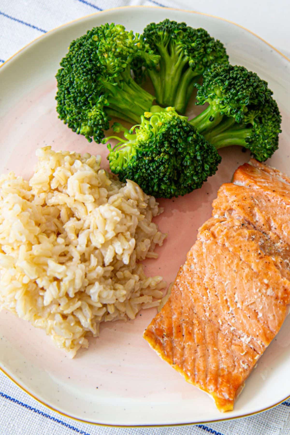 bone broth rice on a plate with broccoli and salmon.