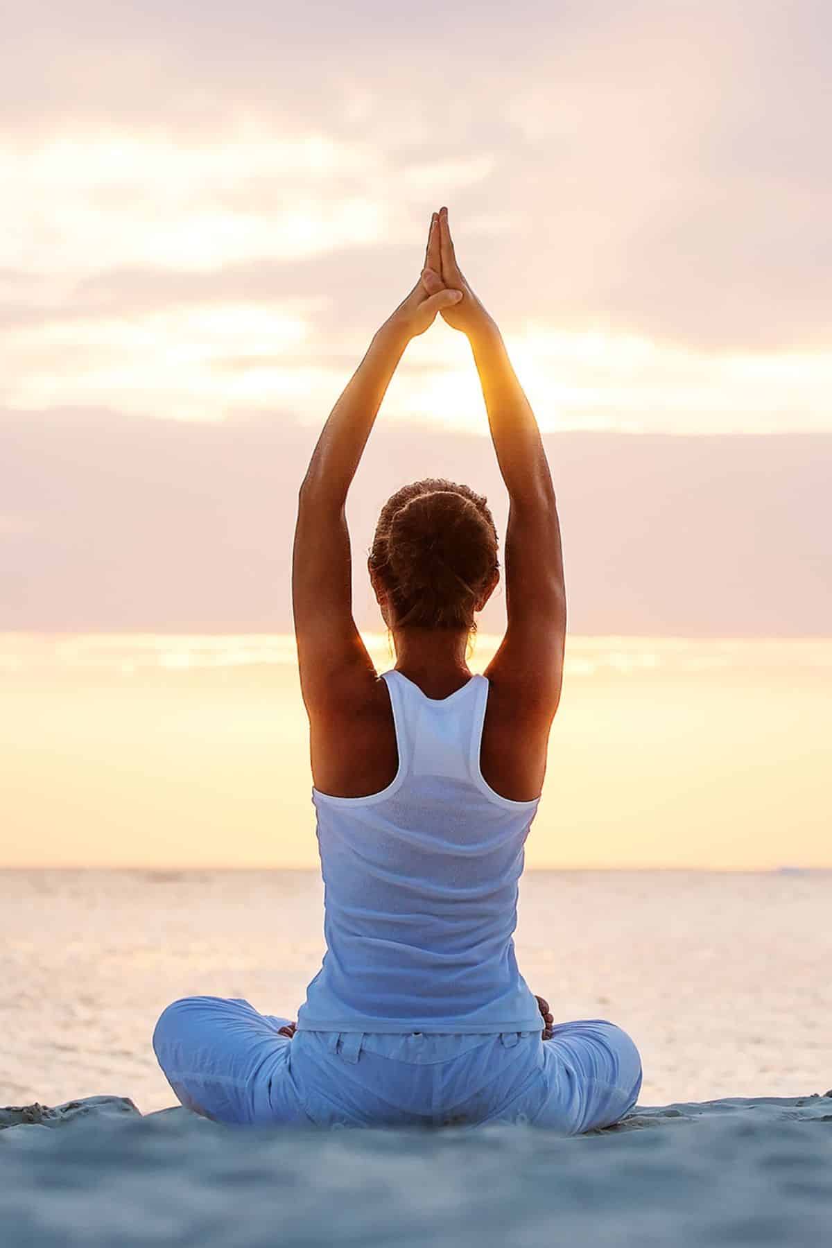 a woman in a yoga pose on the beach.