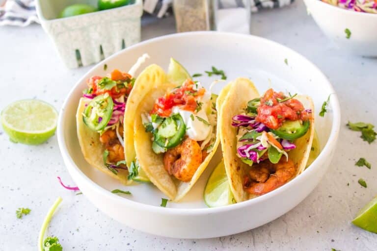 three baja shrimp tacos on a white plate.
