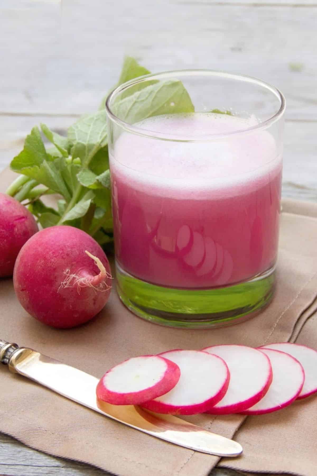 a glass of radish juice next to sliced radishes.