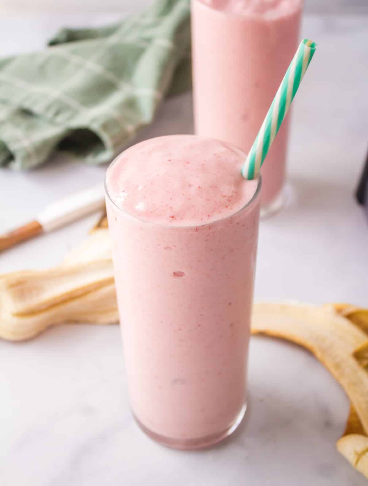 a glass of strawberry banana smoothie with a straw.