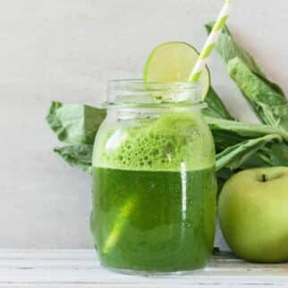 a glass of dandelion green juice with a straw.